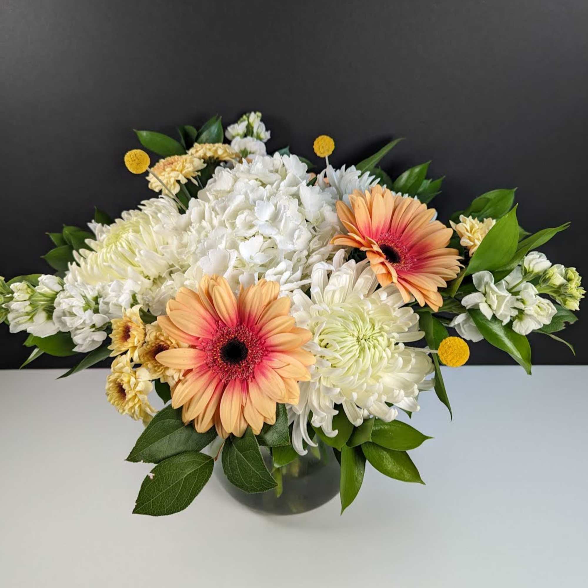 Peach gerbera daisies and white chrysanthemums in a glass vase