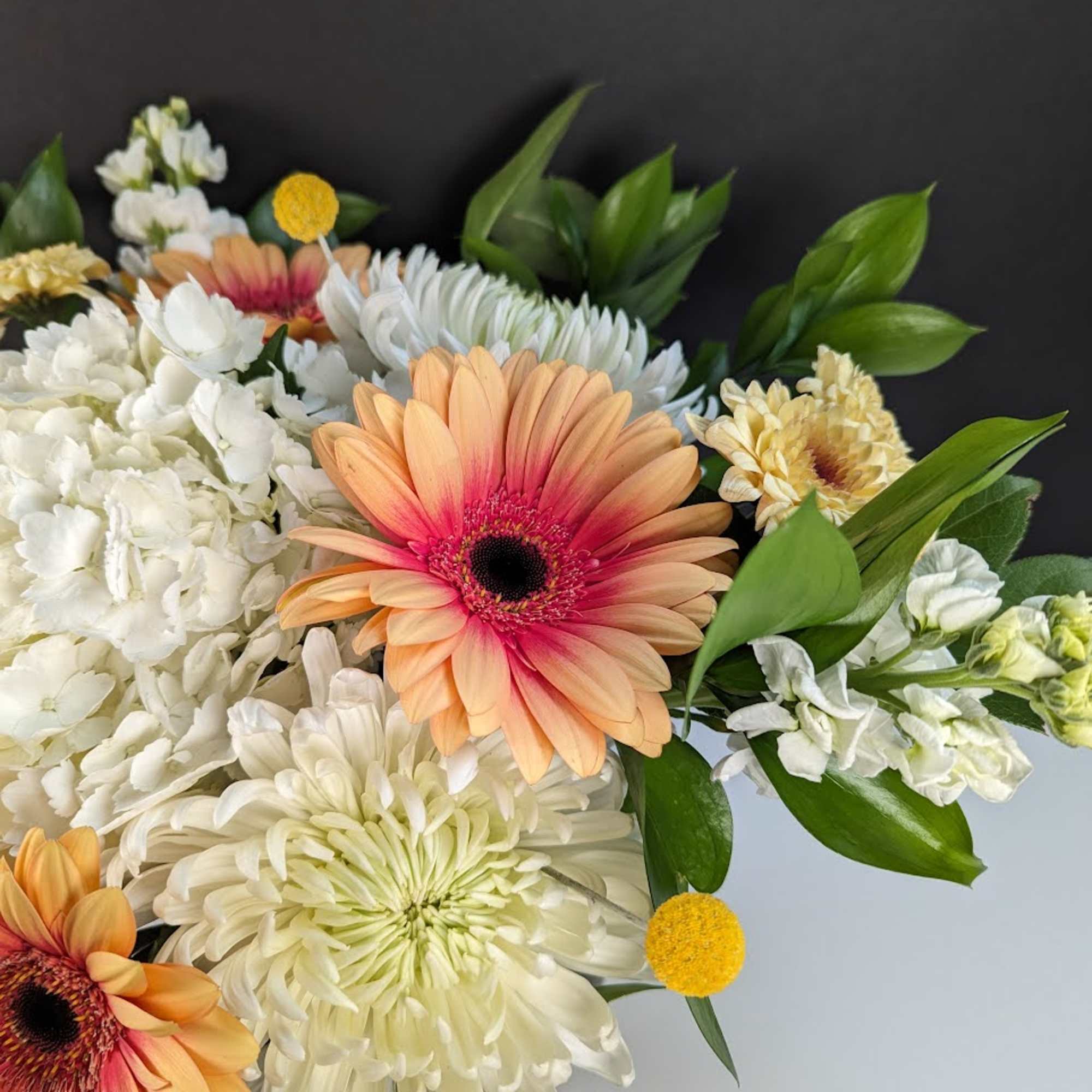 Bouquet of peach gerbera daisies and white chrysanthemums with green leaves