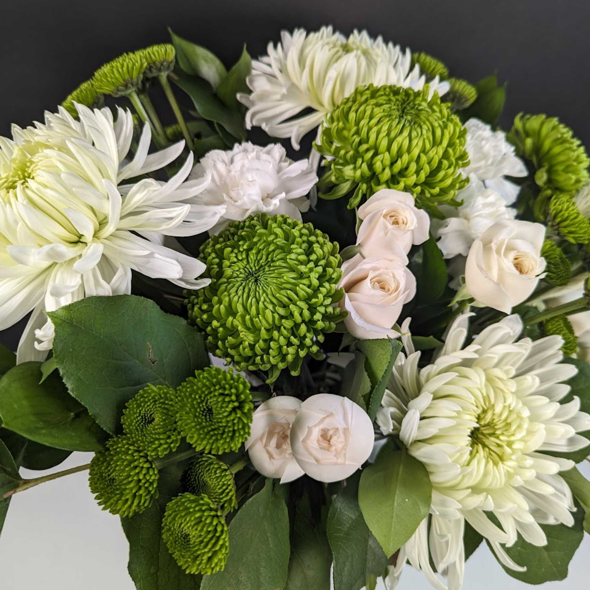 Bouquet of white chrysanthemums, pale roses, and green button mums