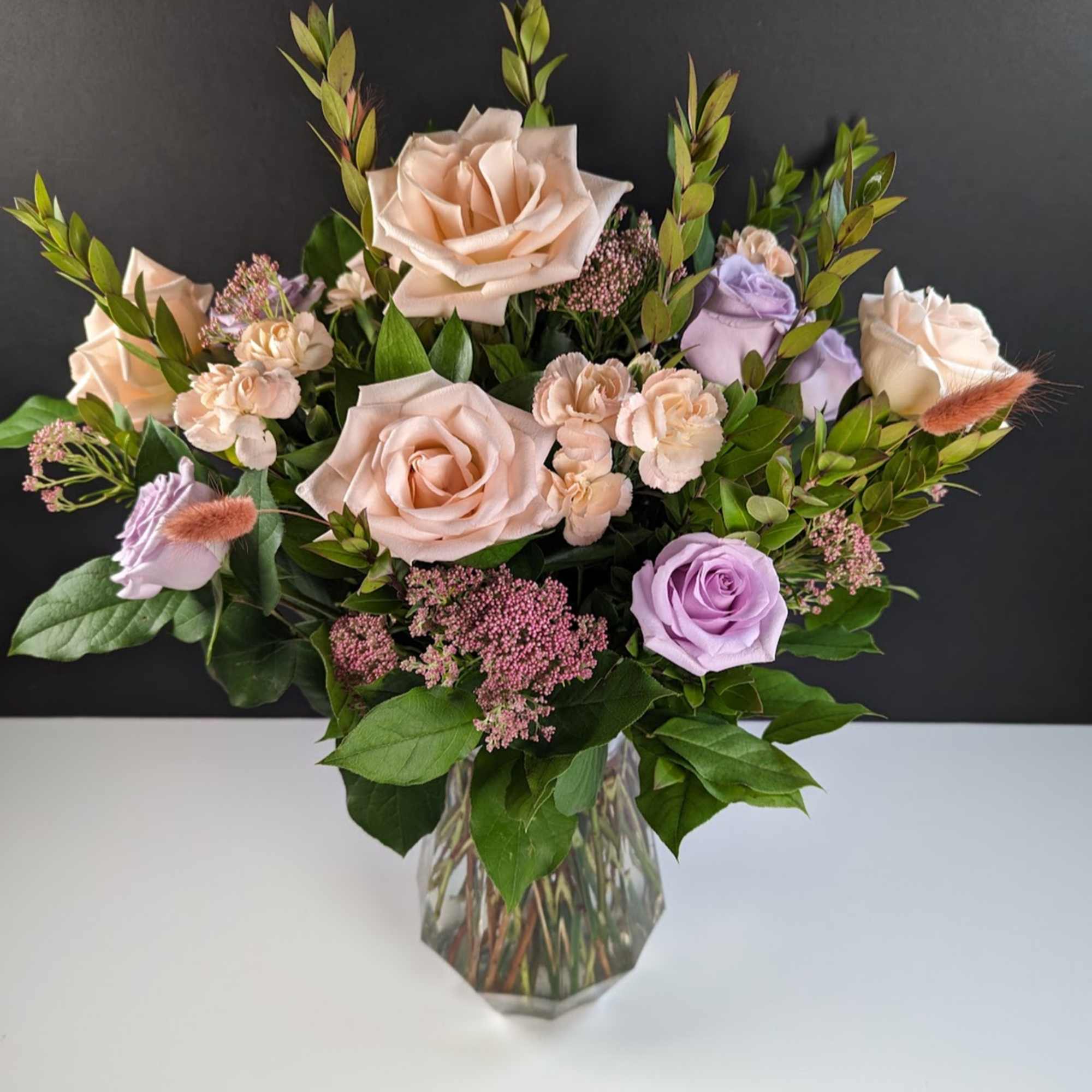 Bouquet of blush and lavender roses in a clear glass vase