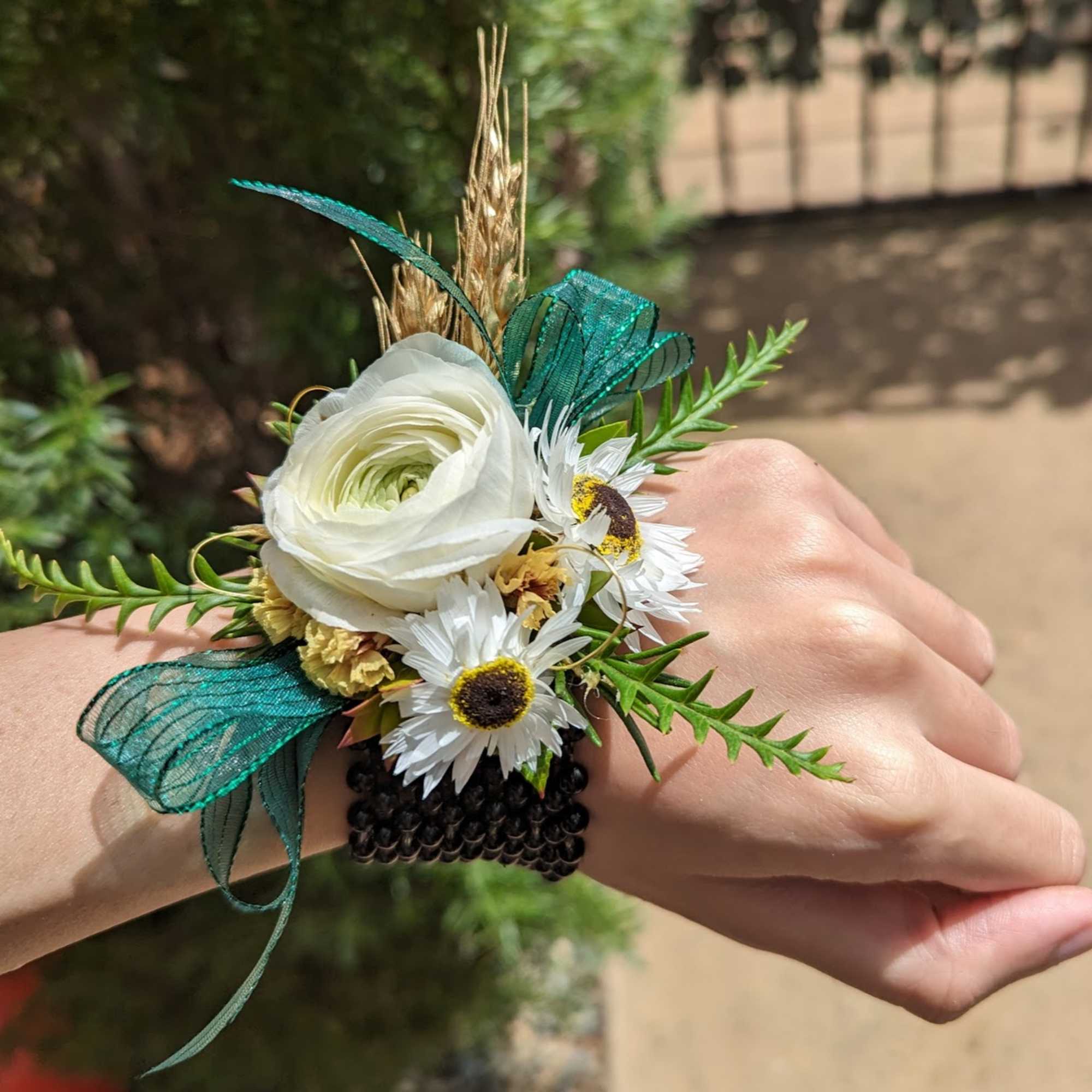 White flower wrist corsage with teal ribbon and small daisies