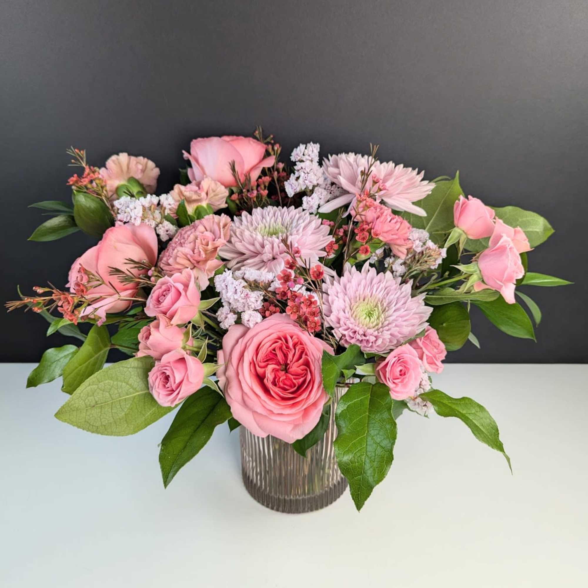 Pink roses and chrysanthemums arranged in a ribbed glass vase
