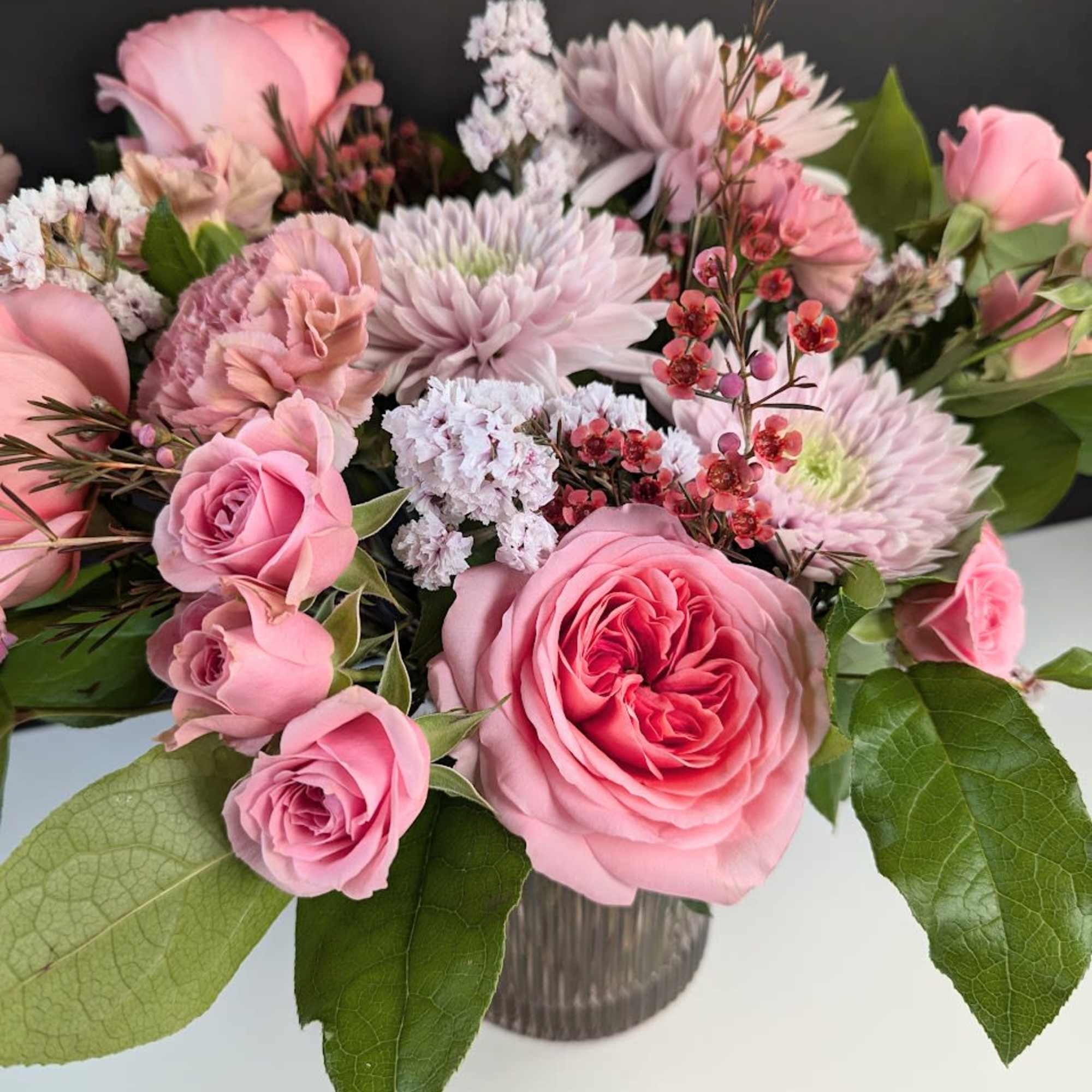 Pink roses and pale blooms arranged in a glass vase