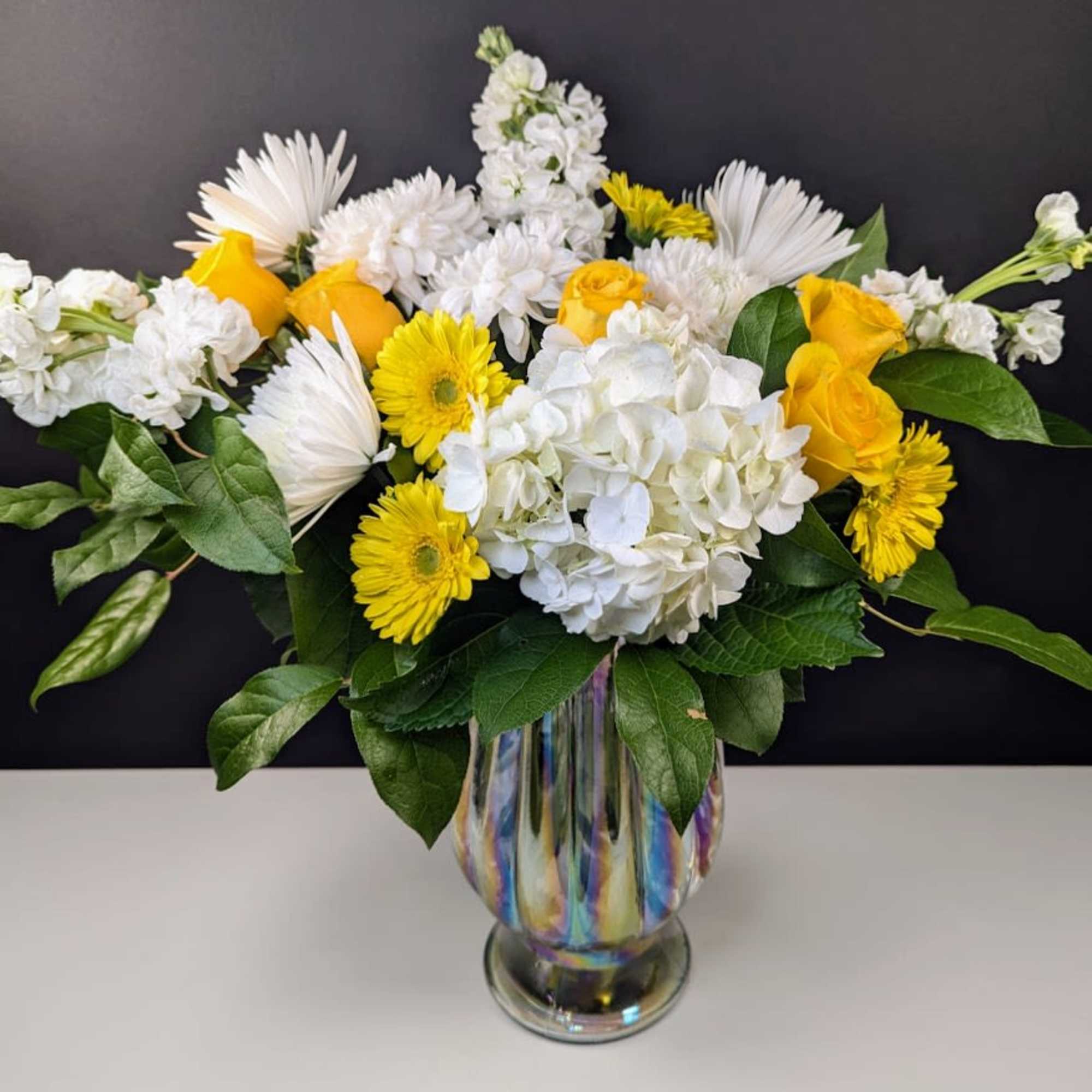 Yellow and white flowers arranged in a glass vase