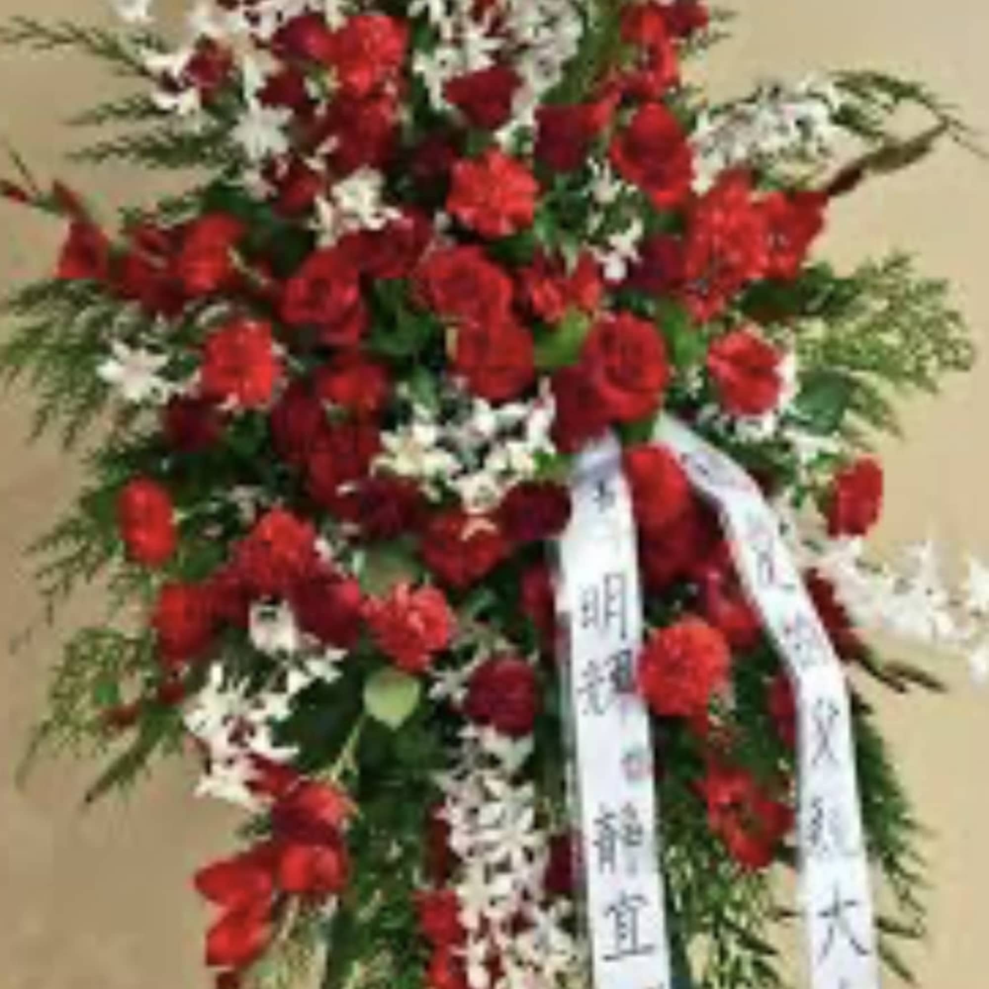 Tall standing floral spray of red and white flowers with ribbon streamers