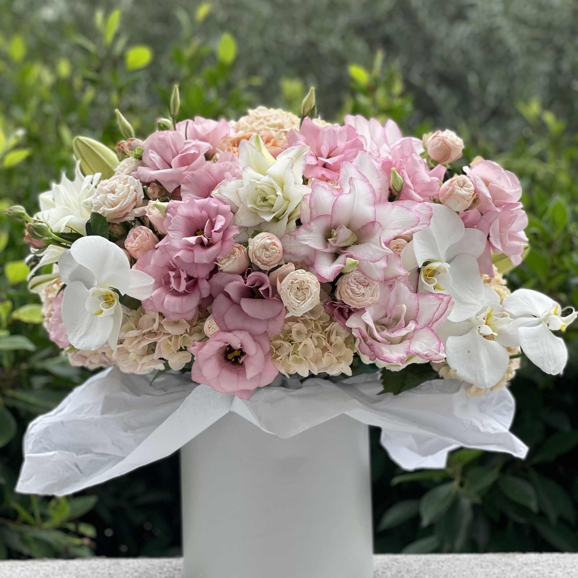 Pink and white floral arrangement in a white hatbox