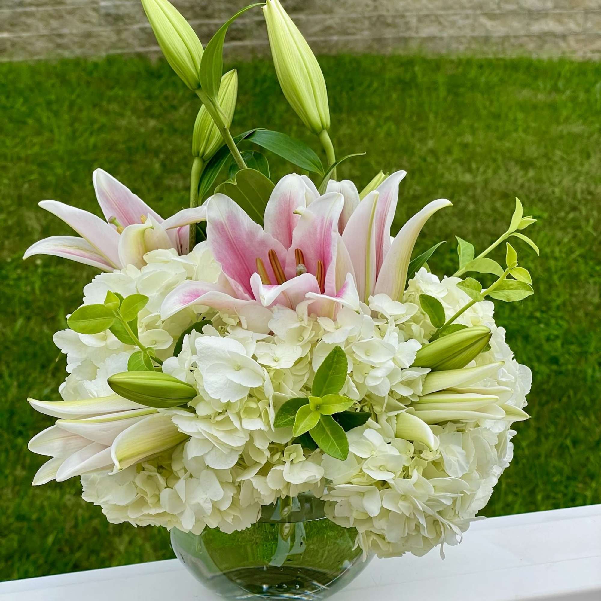 Pink lilies and white hydrangeas in a glass bowl vase