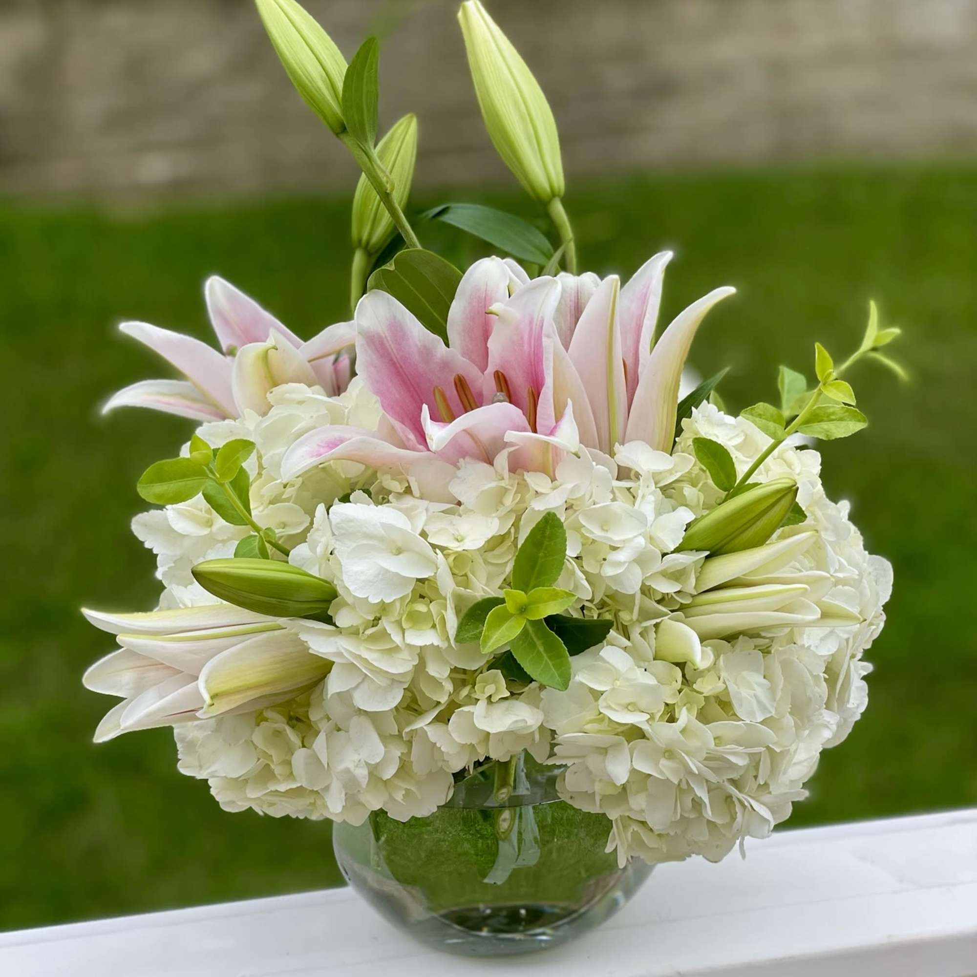 White hydrangeas and pink lilies in a glass vase