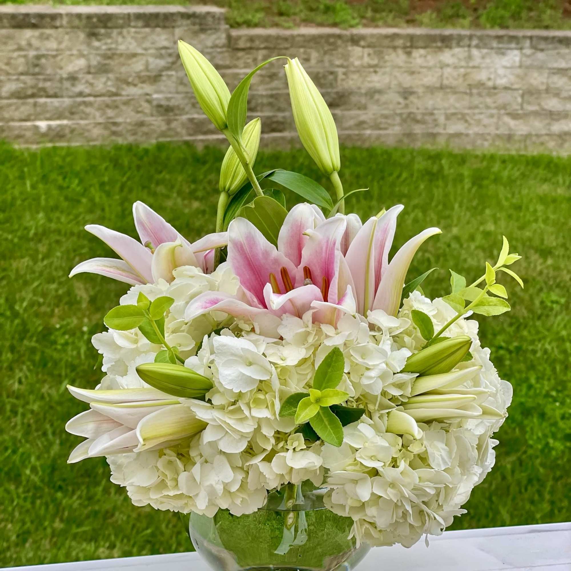 Pink lilies and white hydrangeas in a clear glass vase