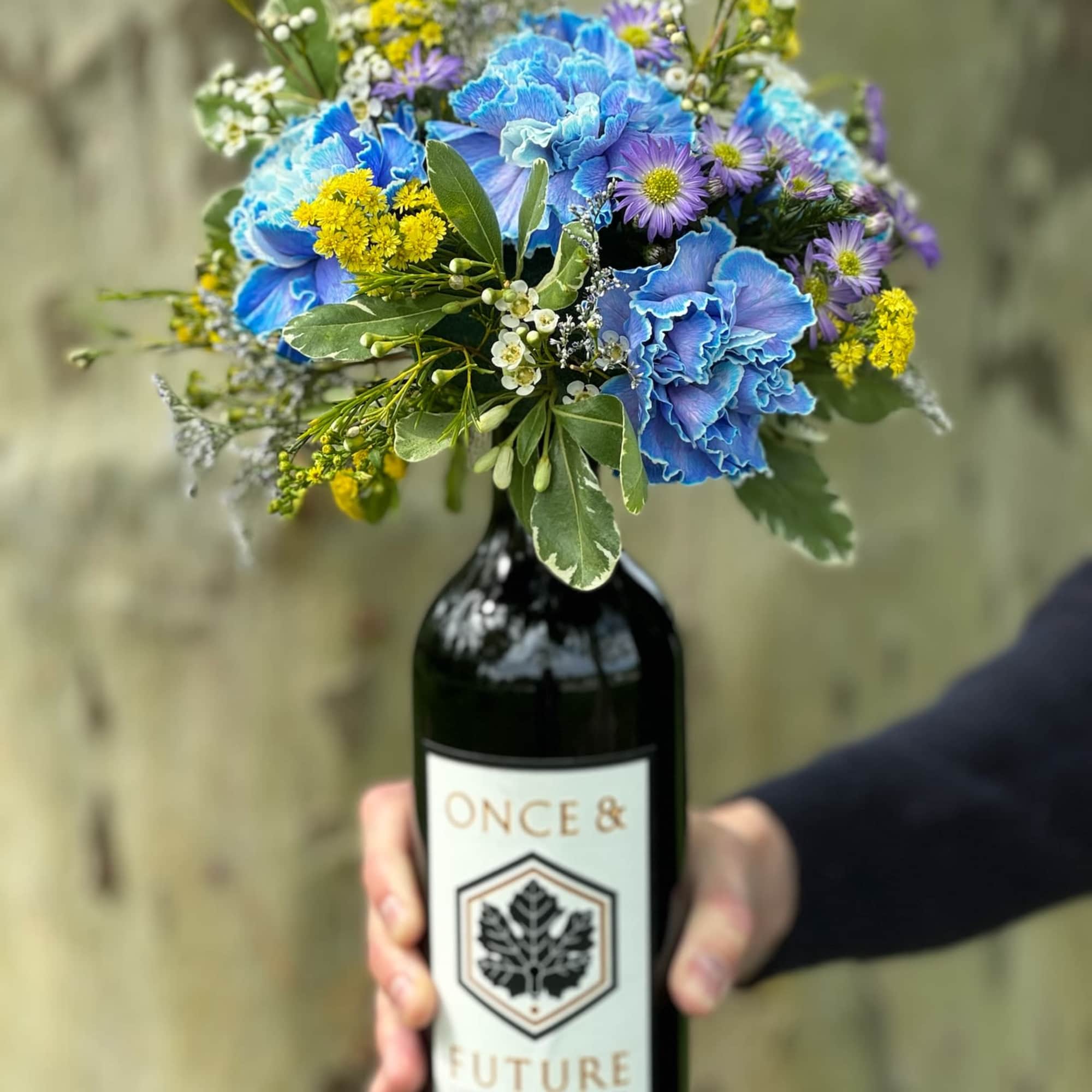 Bouquet of blue and purple flowers arranged in a wine bottle vase