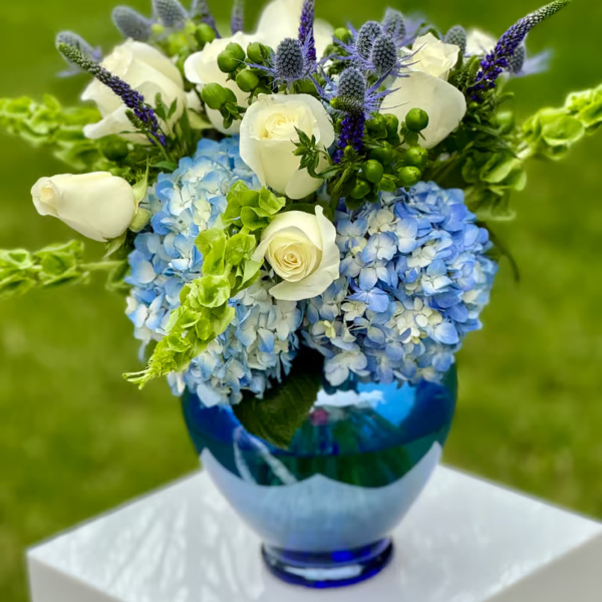 Blue hydrangeas and white roses in a blue glass vase