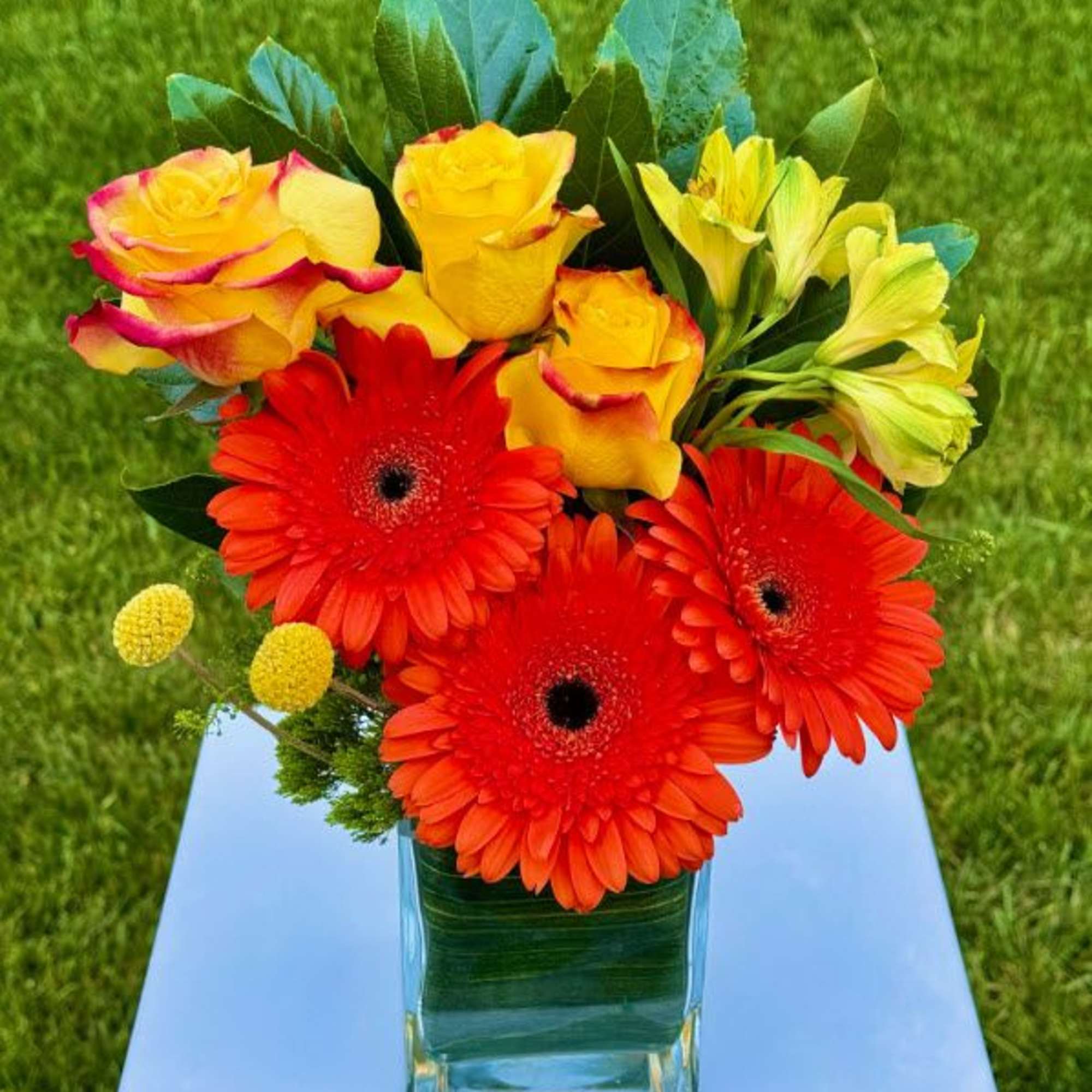 Bright bouquet of red gerbera daisies and yellow roses in a glass vase, photo 6 of 6