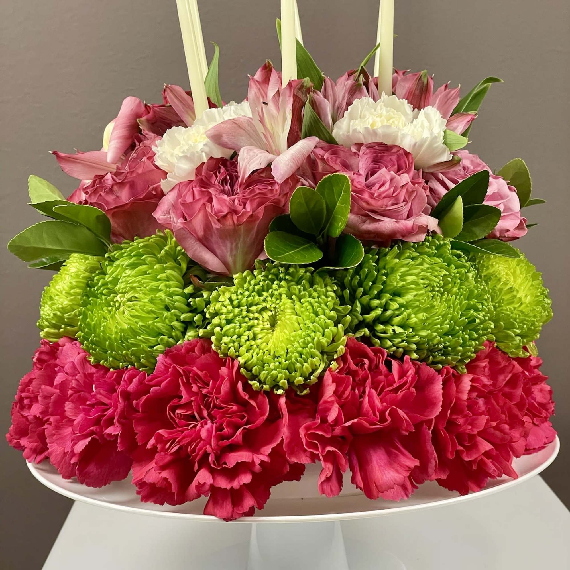 Pink and green floral centerpiece with white candles on a pedestal stand, photo 3 of 3