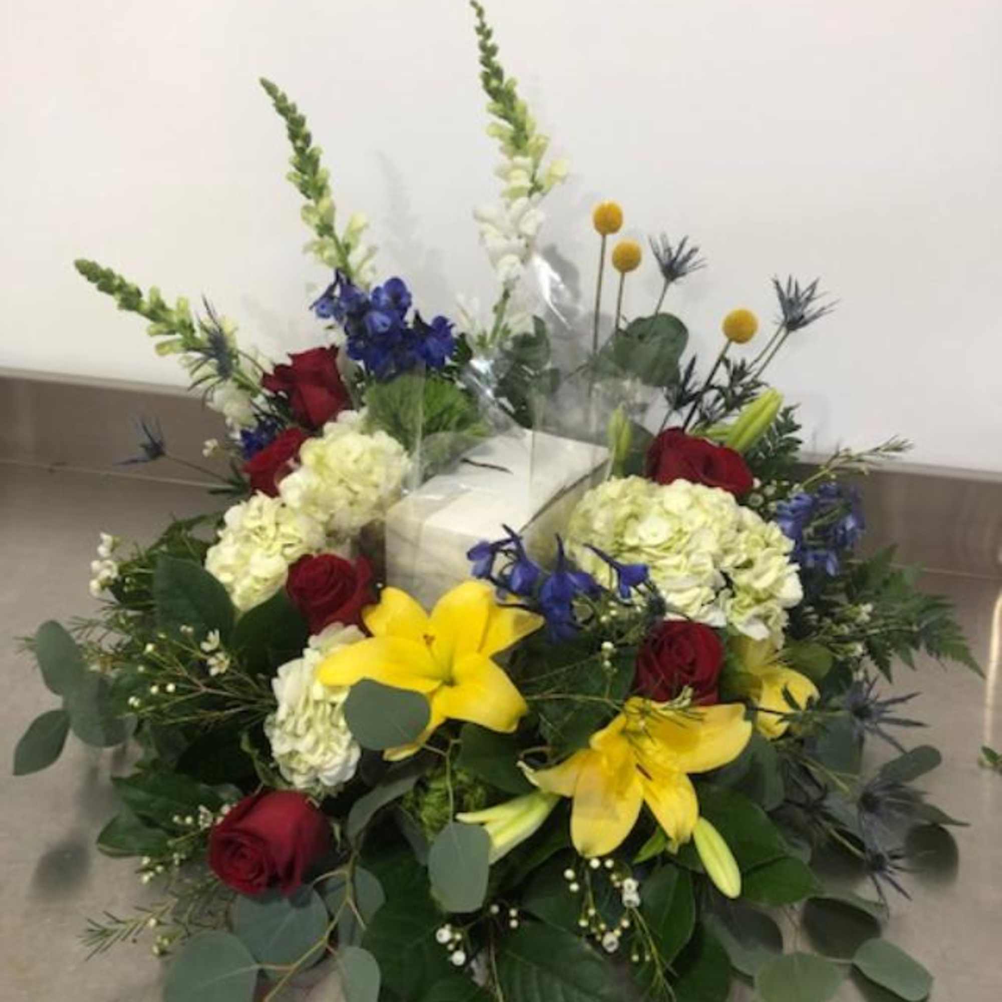 Floral arrangement with red roses, yellow lilies, and white hydrangeas