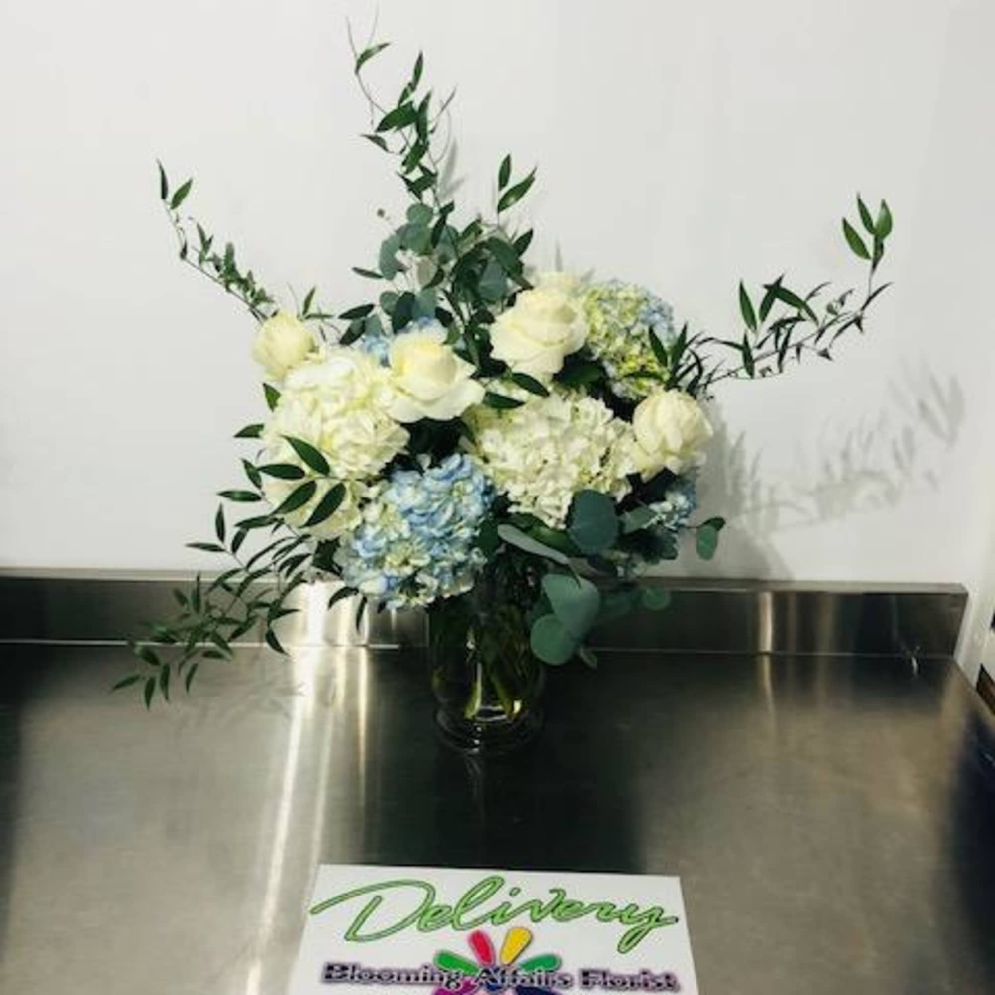 White and blue floral arrangement in a glass vase