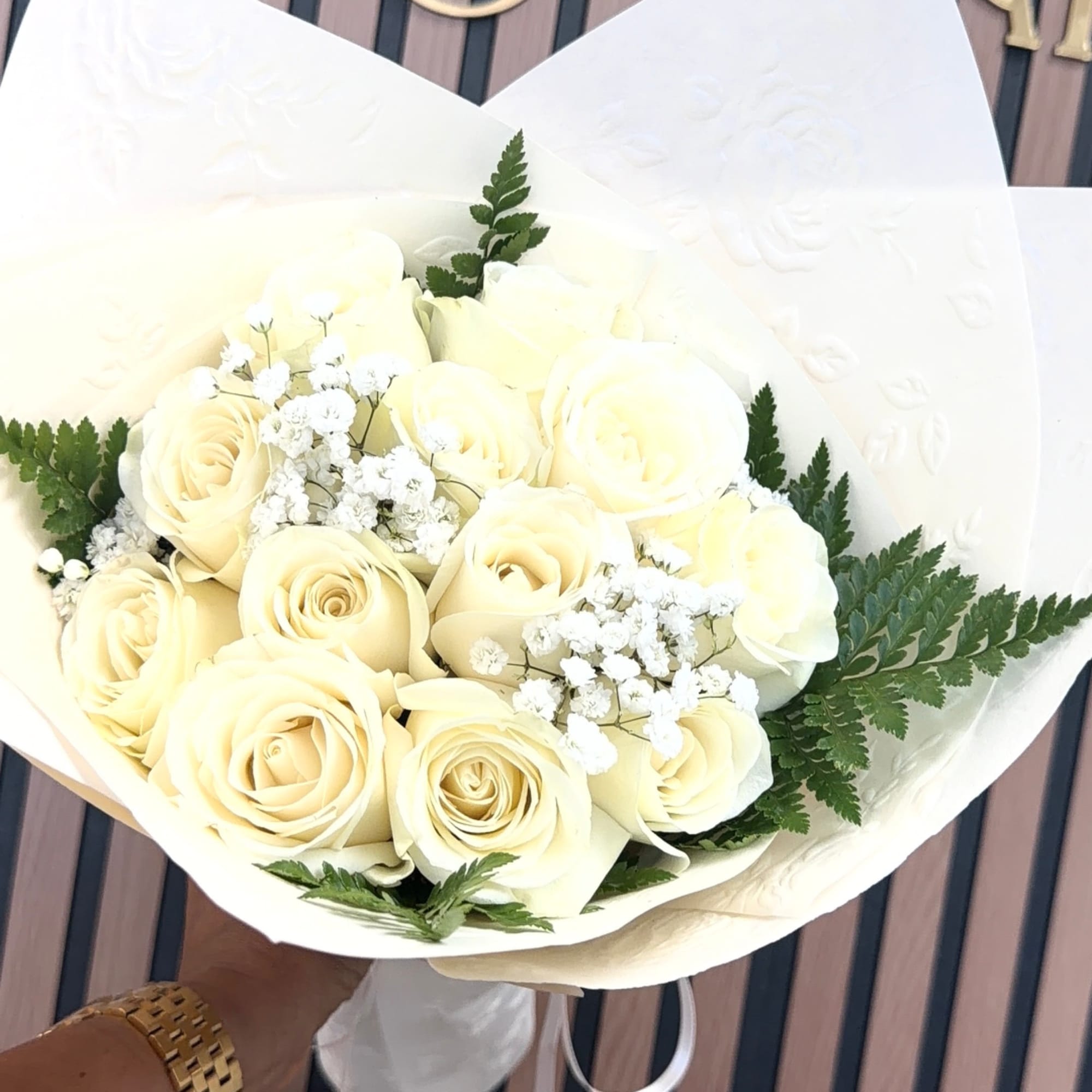 Bouquet of cream roses with small white filler flowers and fern foliage