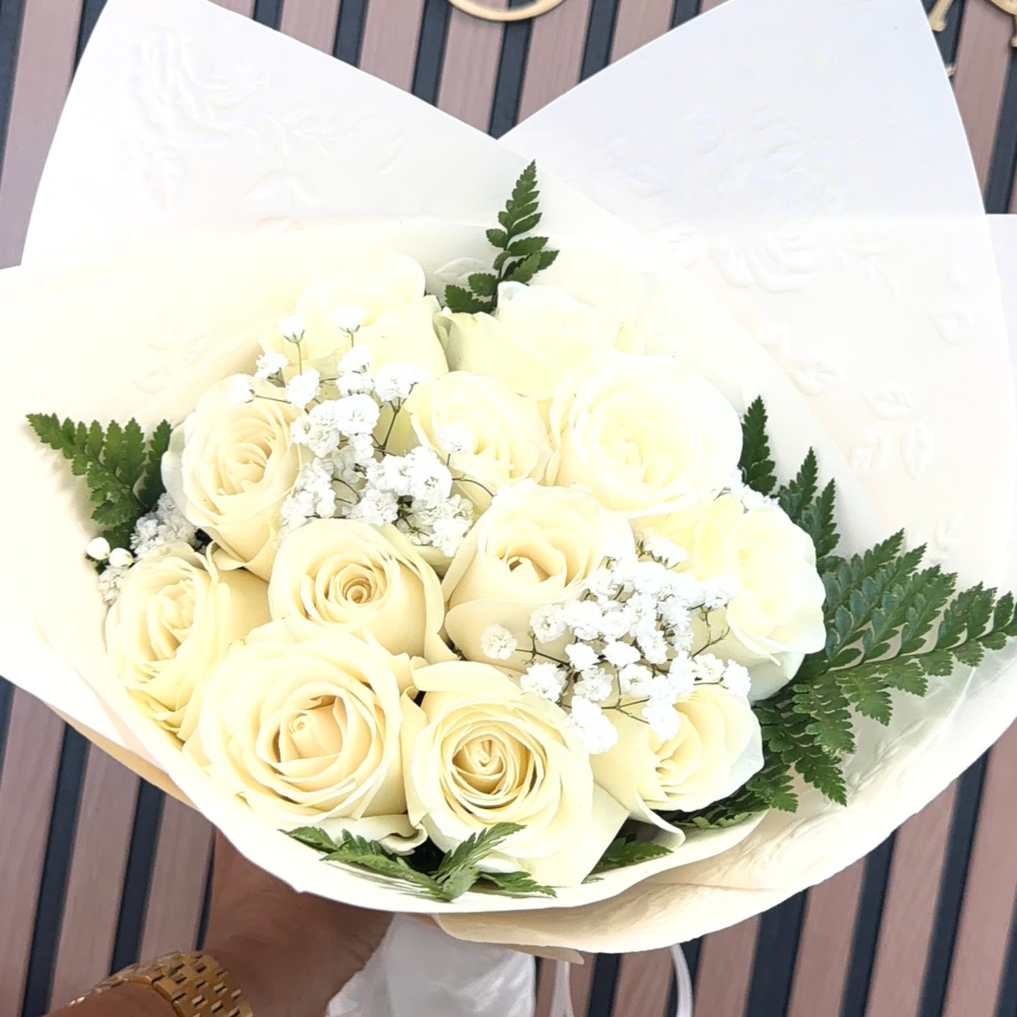 Bouquet of cream roses with white filler flowers wrapped in white paper