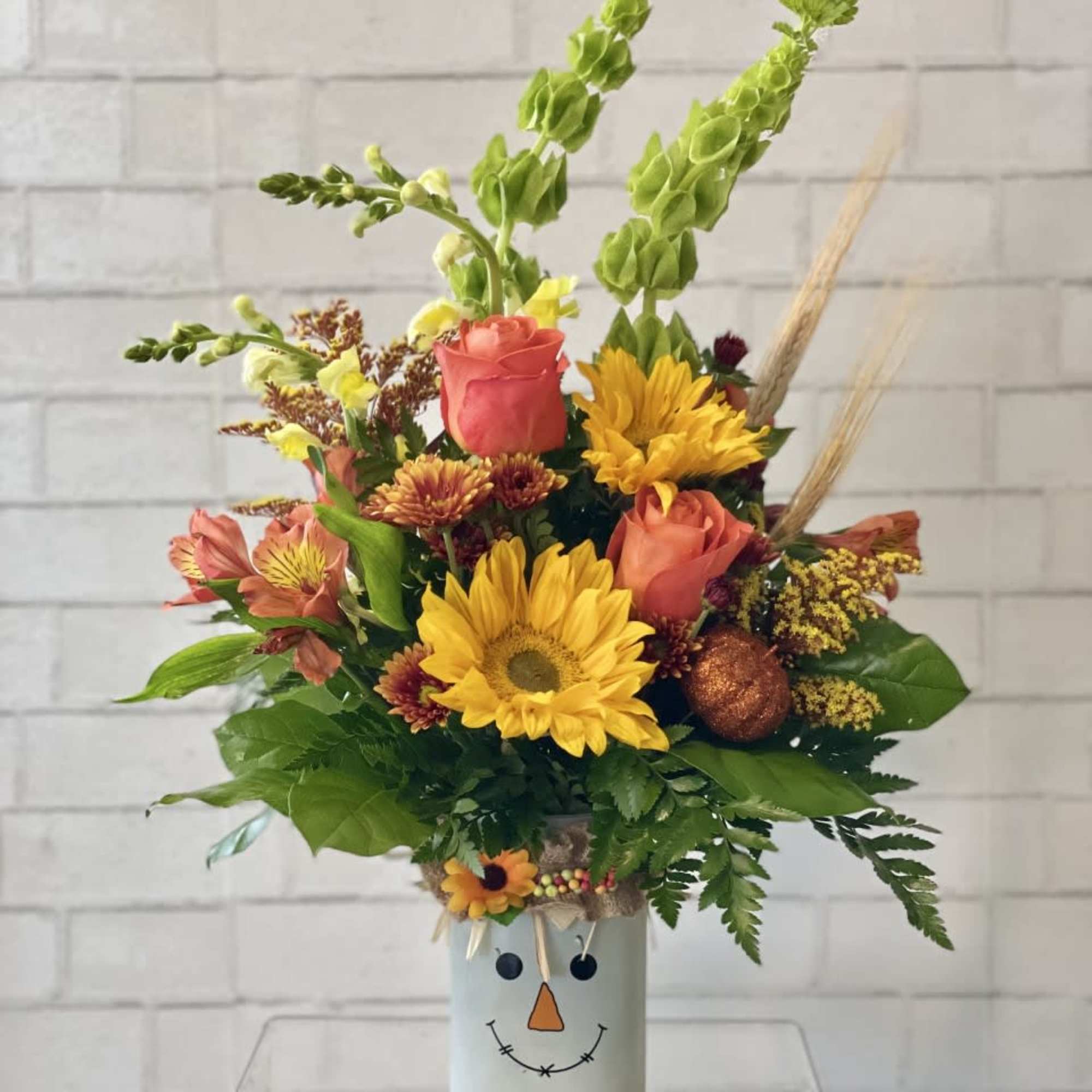 A colorful vase filled to the brim with fall flowers and foliage., photo 2 of 2