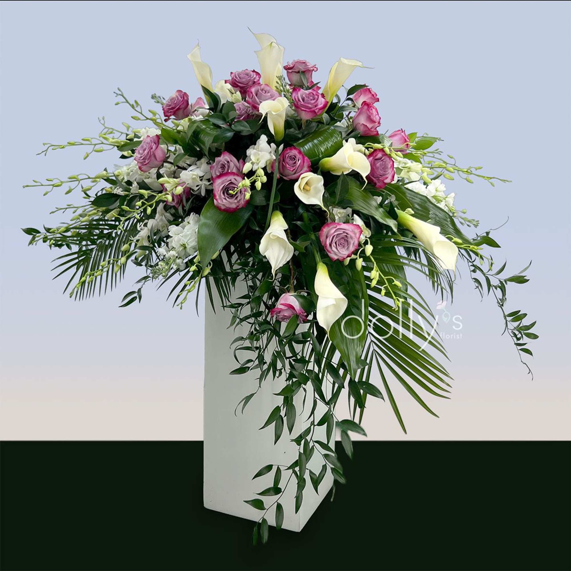 A dramatic cascading casket spray of magenta roses and ivory calla lilies, photo 3 of 3