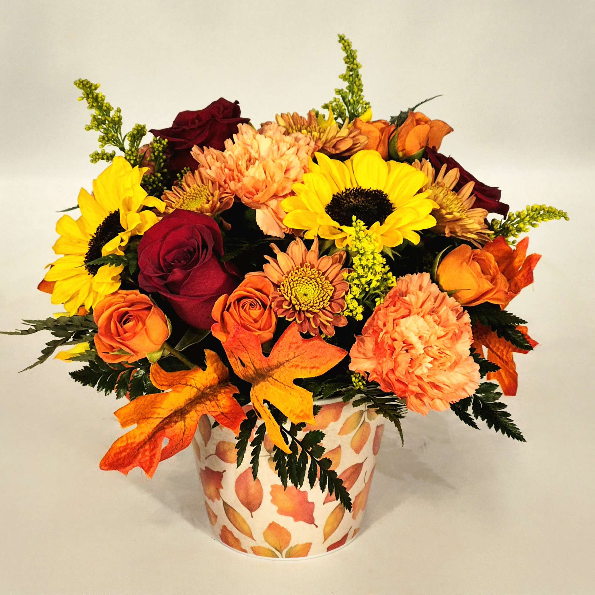 Fall bouquet of sunflowers, roses, and mums in a leaf-patterned vase