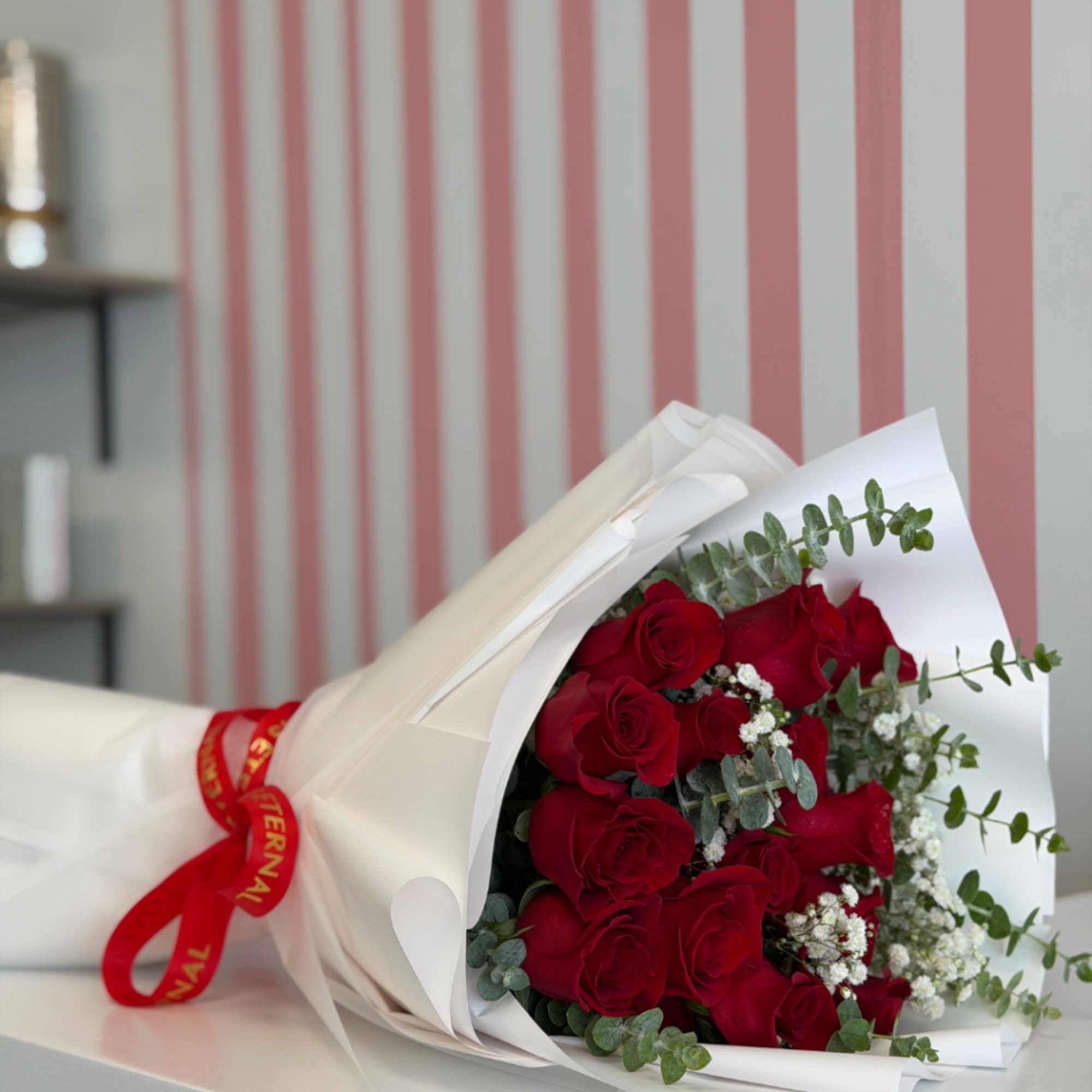 Bouquet of red roses wrapped in white paper with a red ribbon