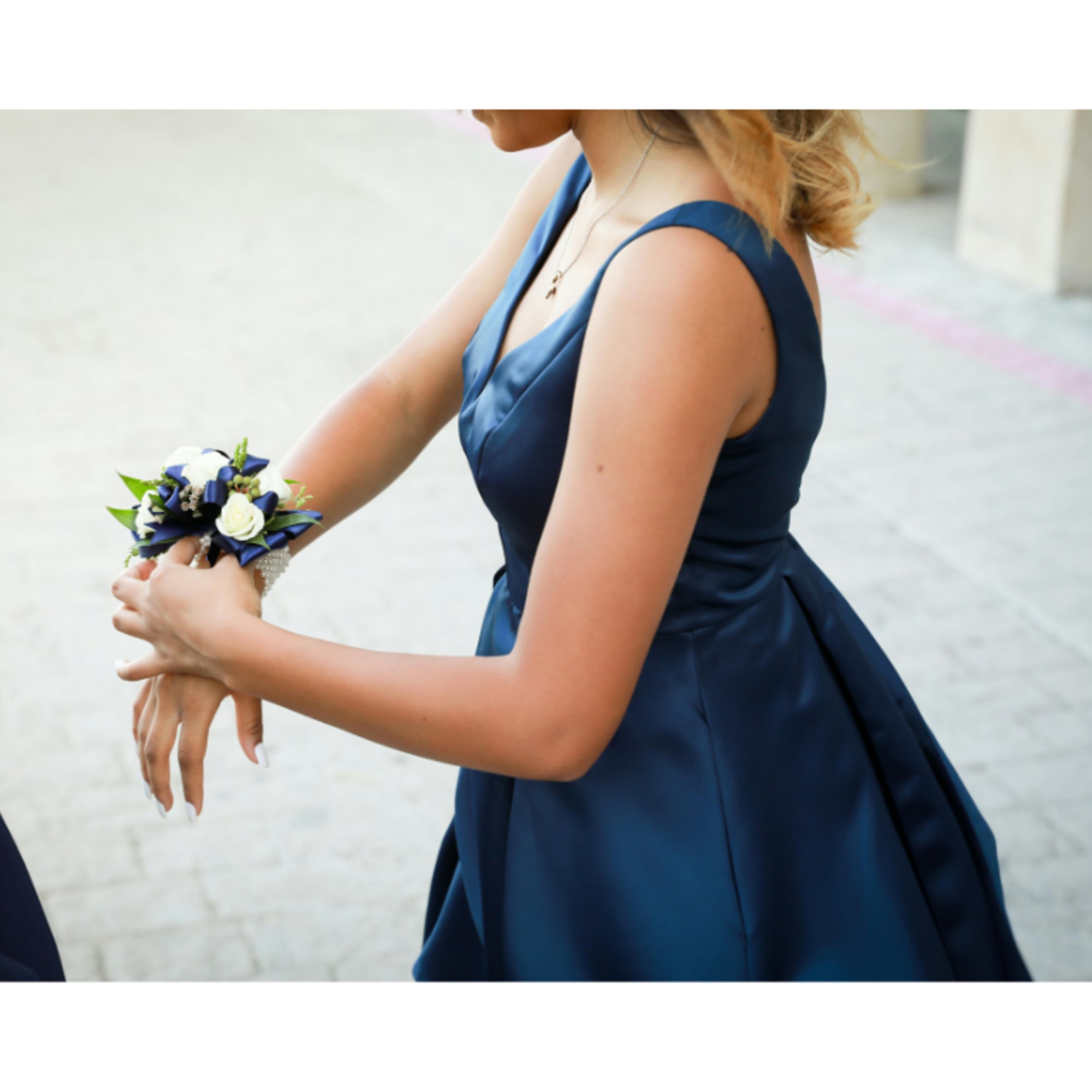 Woman in a navy dress wearing a blue and white wrist corsage