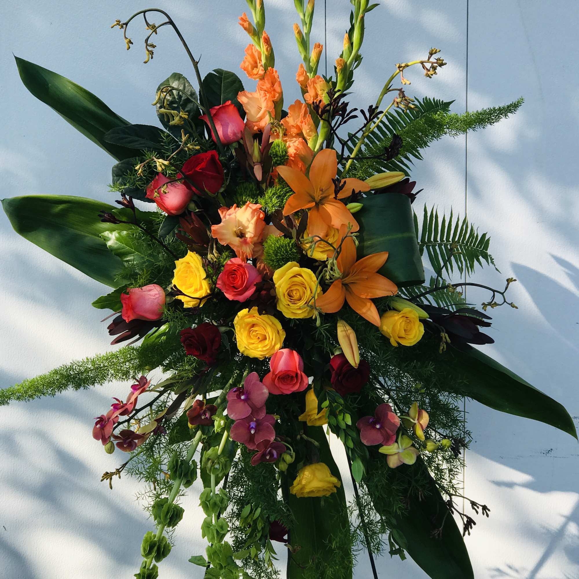 Tall standing floral spray with orange, yellow, and pink blooms
