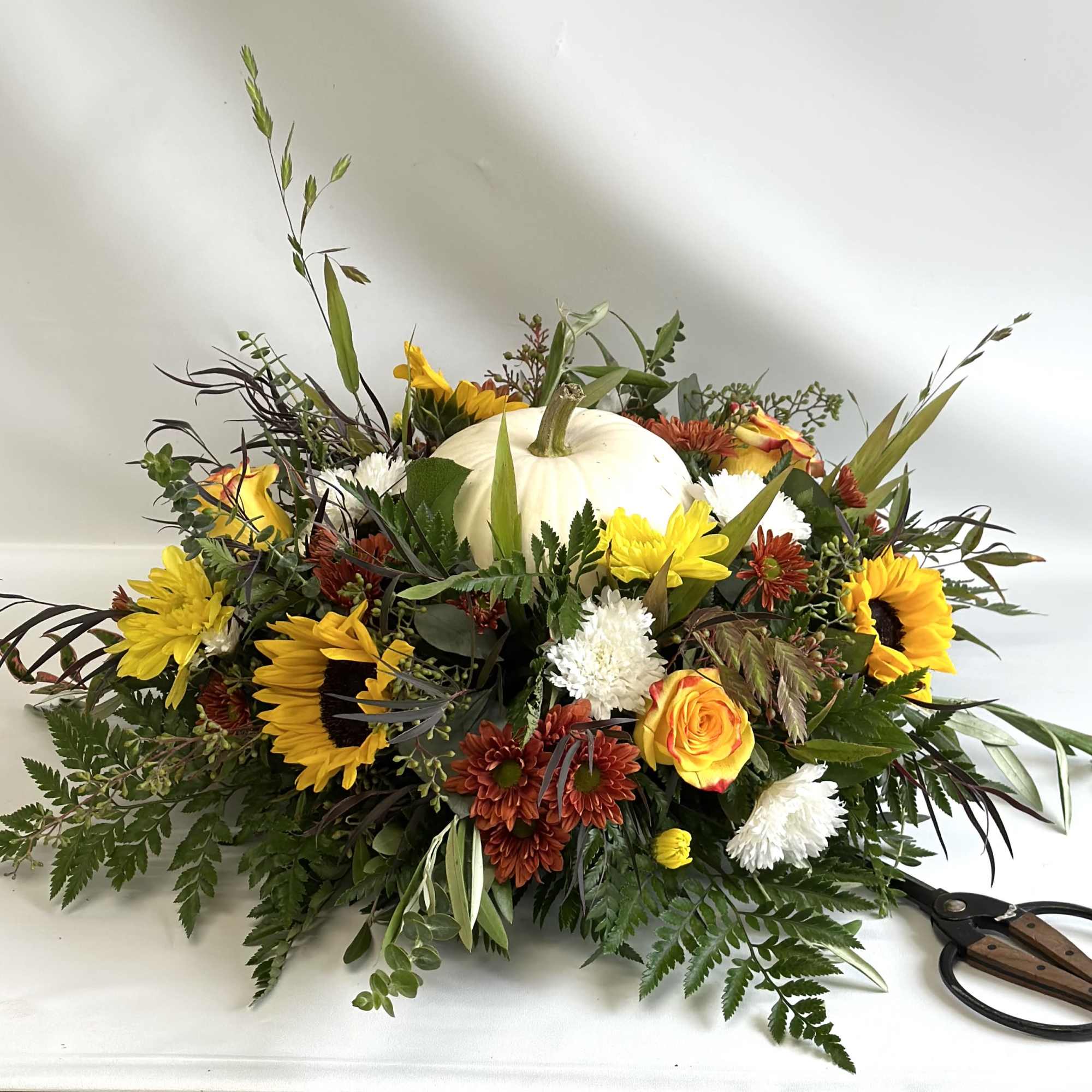 Autumn floral arrangement with a white pumpkin centerpiece and sunflowers