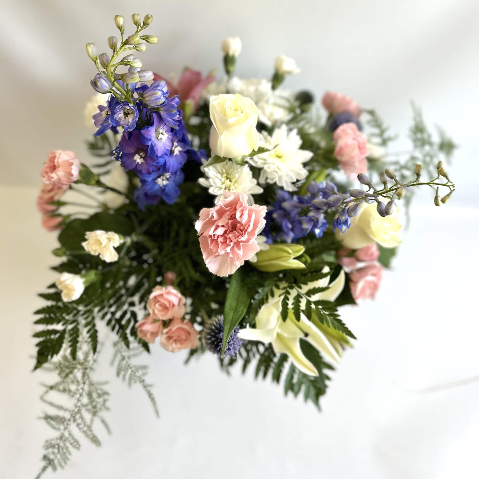 Mixed bouquet with roses, carnations, lilies, and blue delphinium