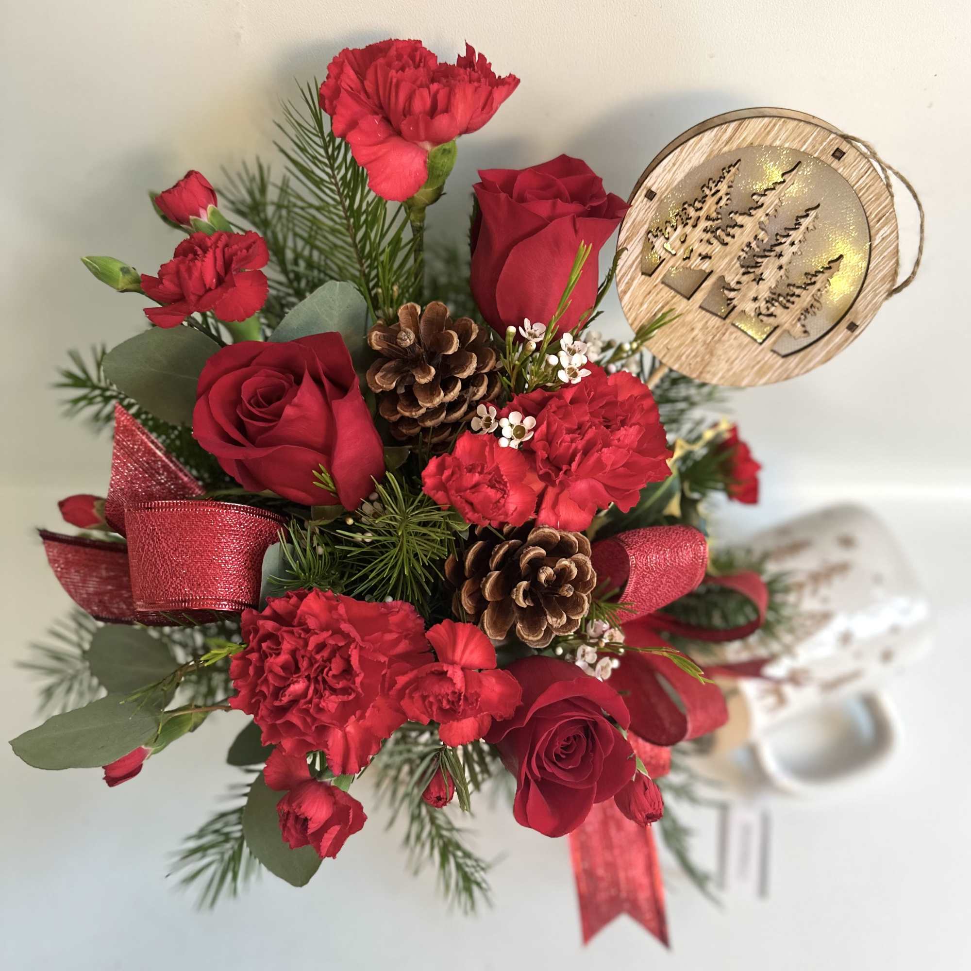Red roses and carnations with pinecones and a ribbon bow