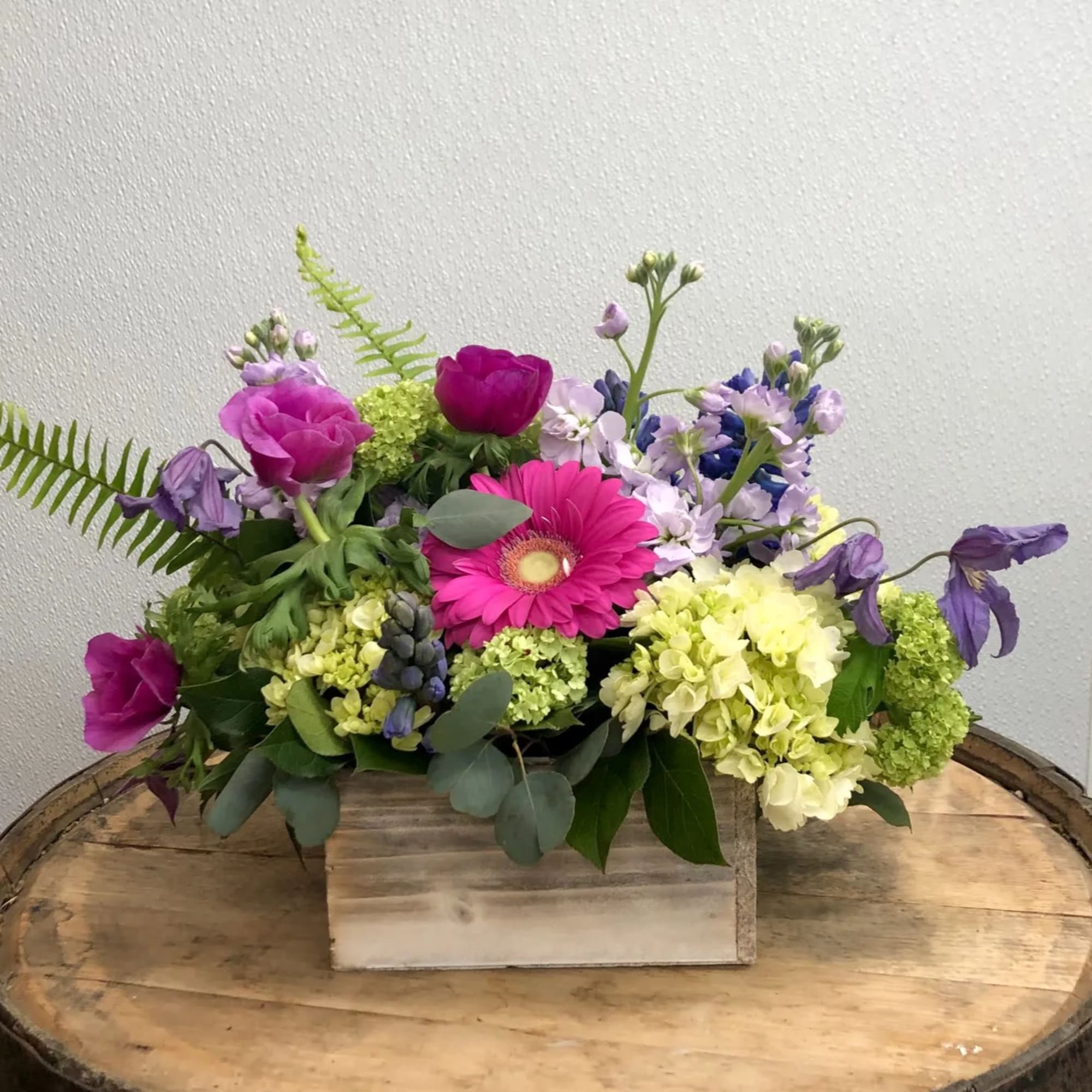 Mixed bouquet with pink and purple flowers in a wooden box