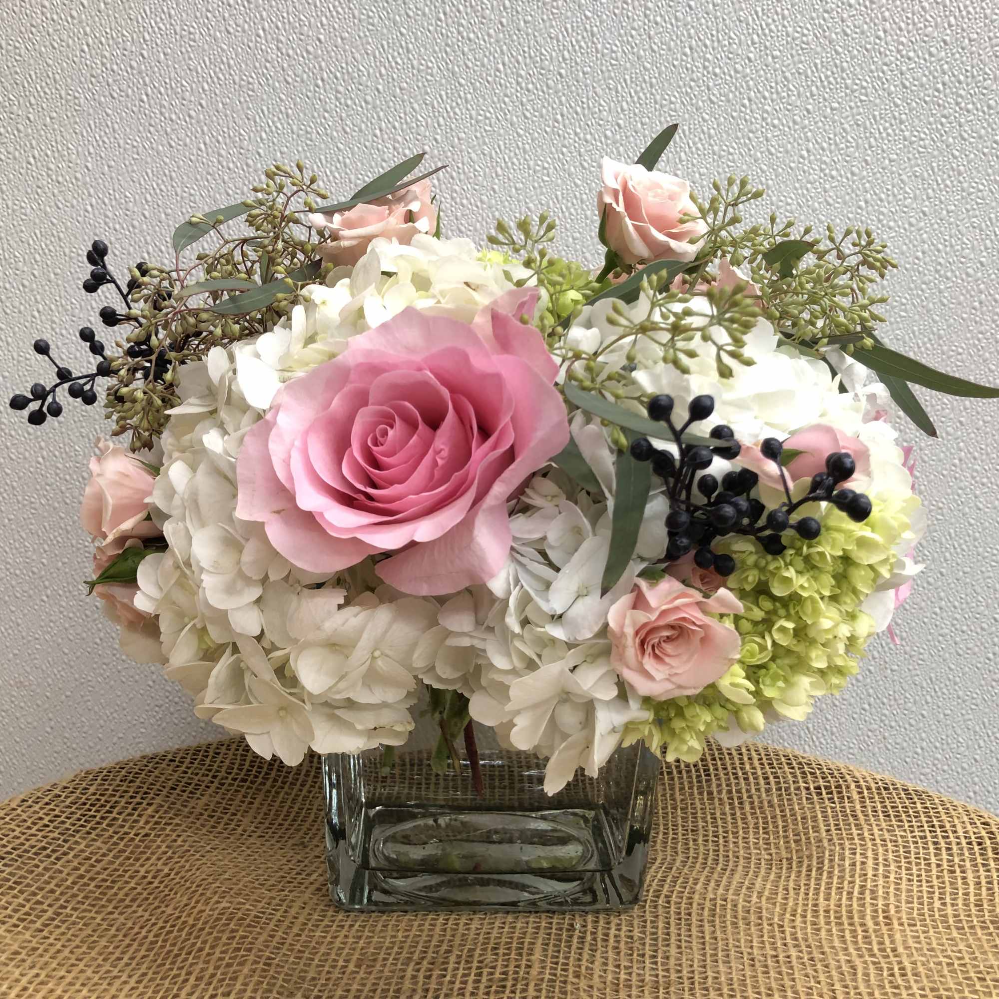 Pink and white rose arrangement in a square glass vase
