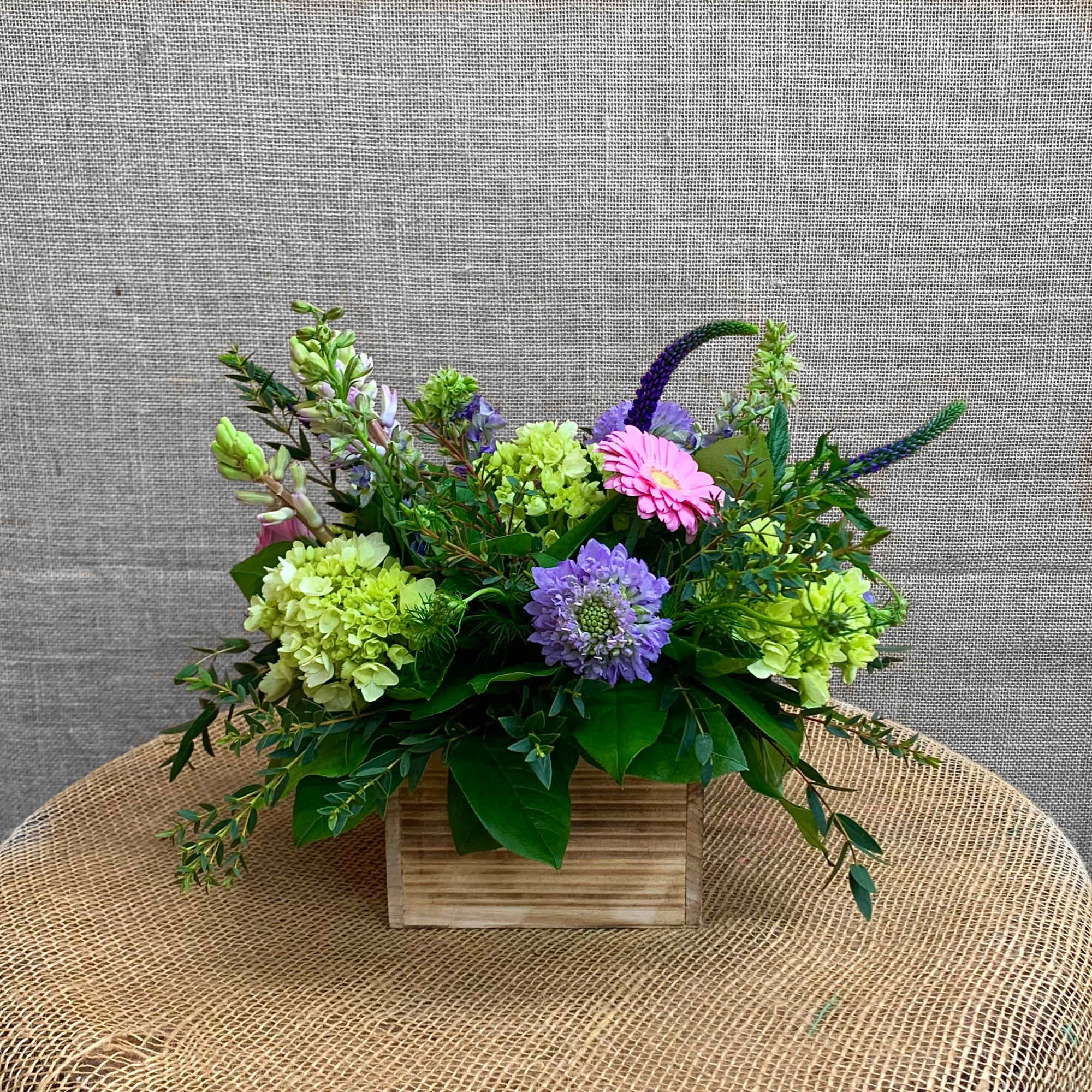 Mixed bouquet in a wooden box with pink and purple blooms
