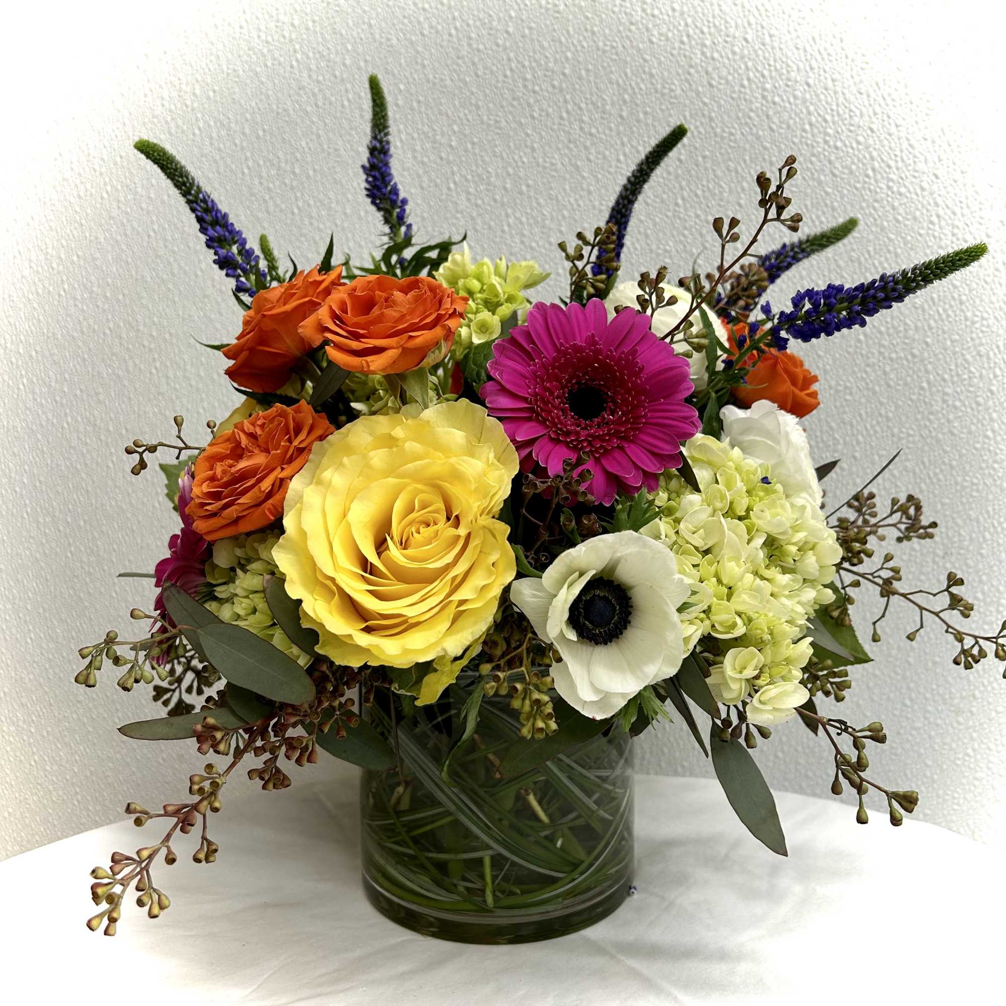 Colorful bouquet of roses, gerbera daisies, and hydrangeas in a glass vase