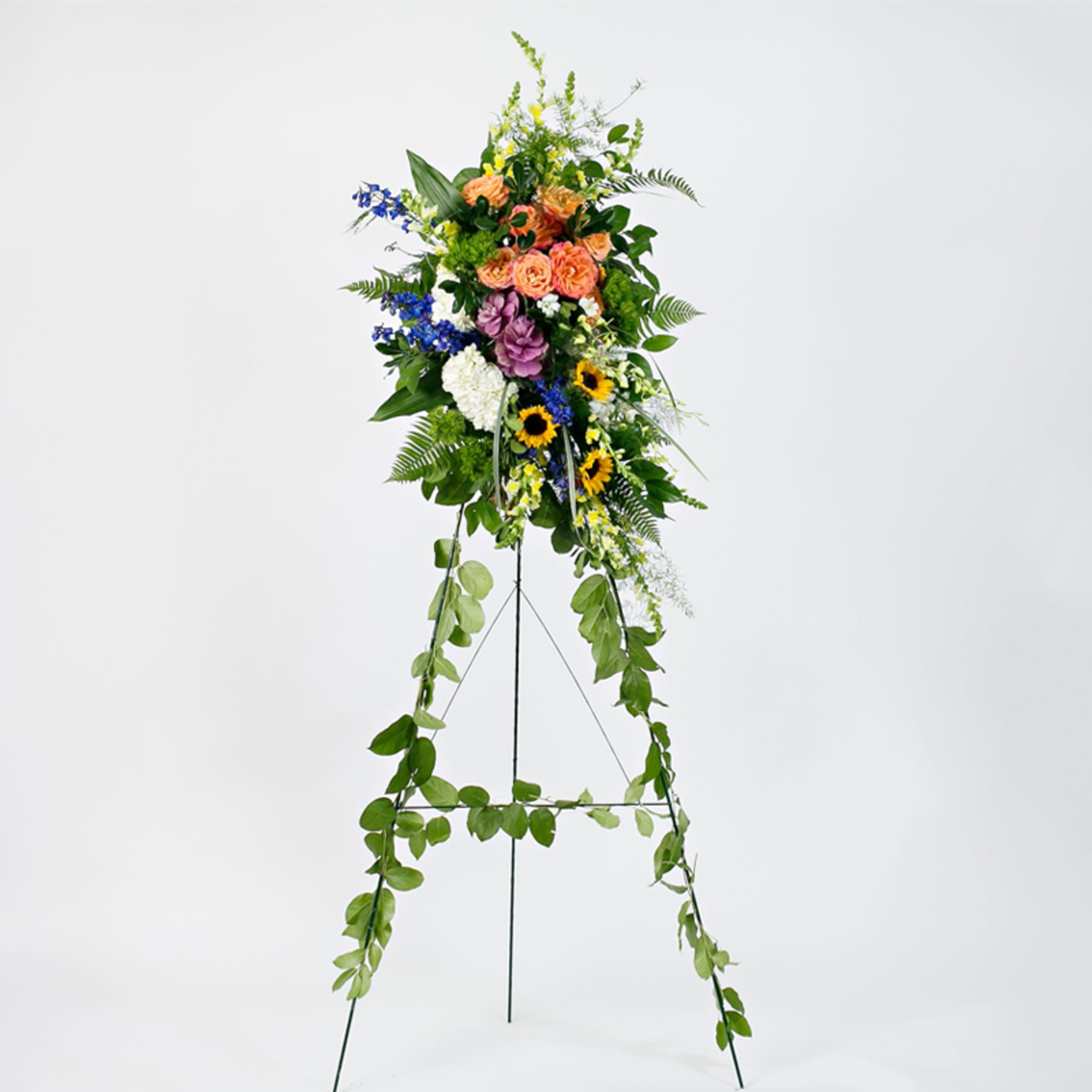 Standing floral easel spray with mixed colorful flowers and trailing greenery