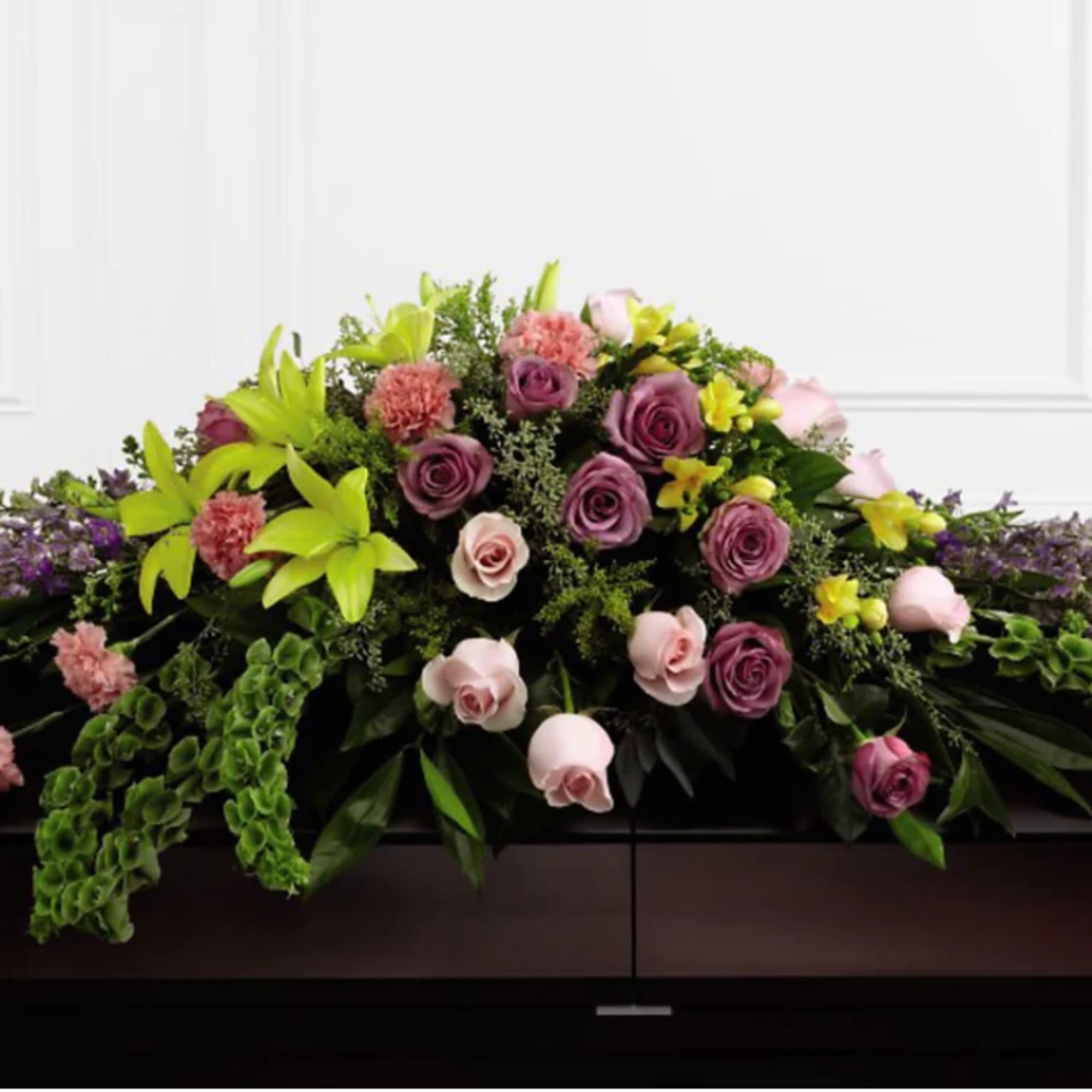 Casket spray with pink and purple roses and lilies