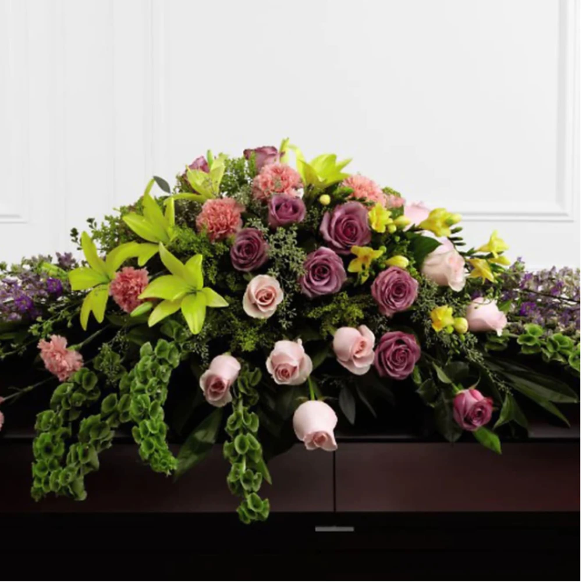 Large floral casket spray with pink and purple roses and bright green lilies