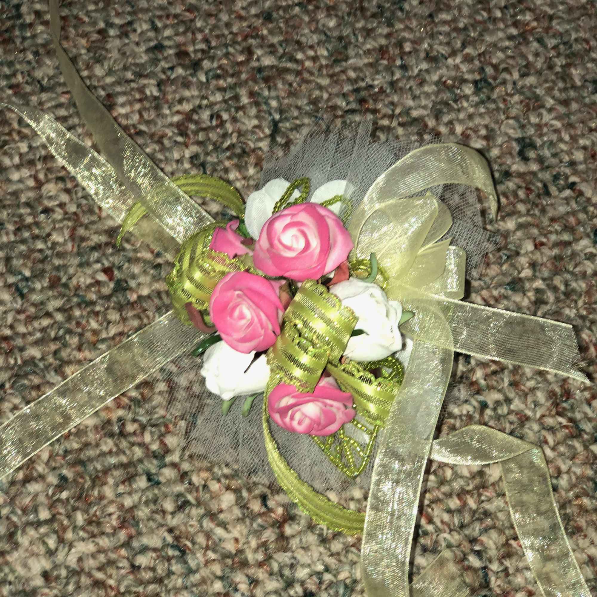 Small pink and white rose corsage with ribbon on carpet
