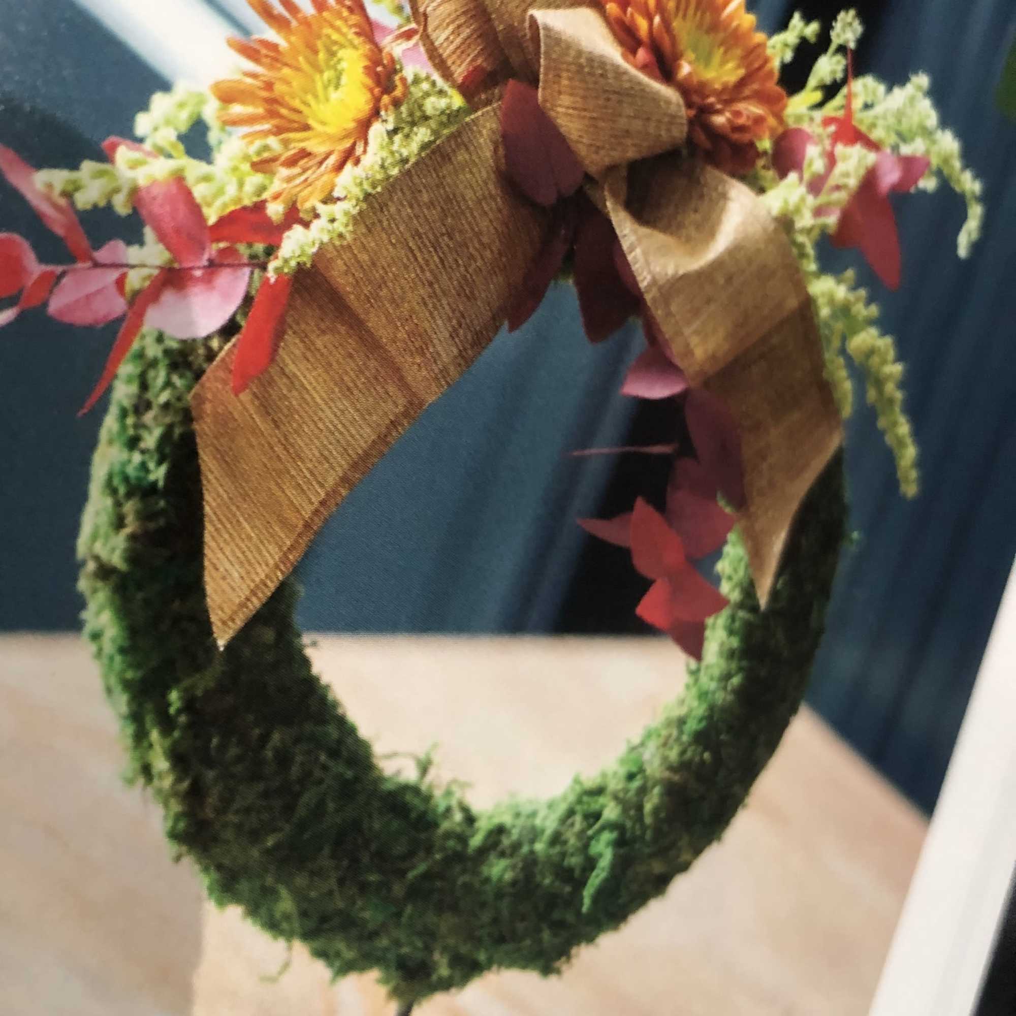 Floral wreath with orange daisies and a large brown bow