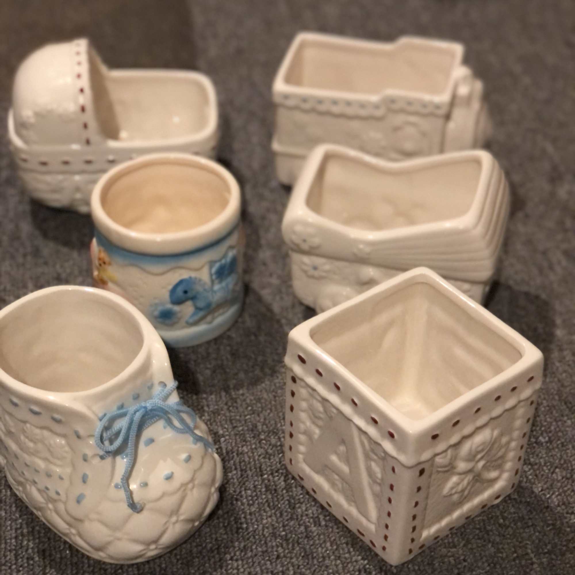 Six small ceramic containers with decorative shapes and pastel accents
