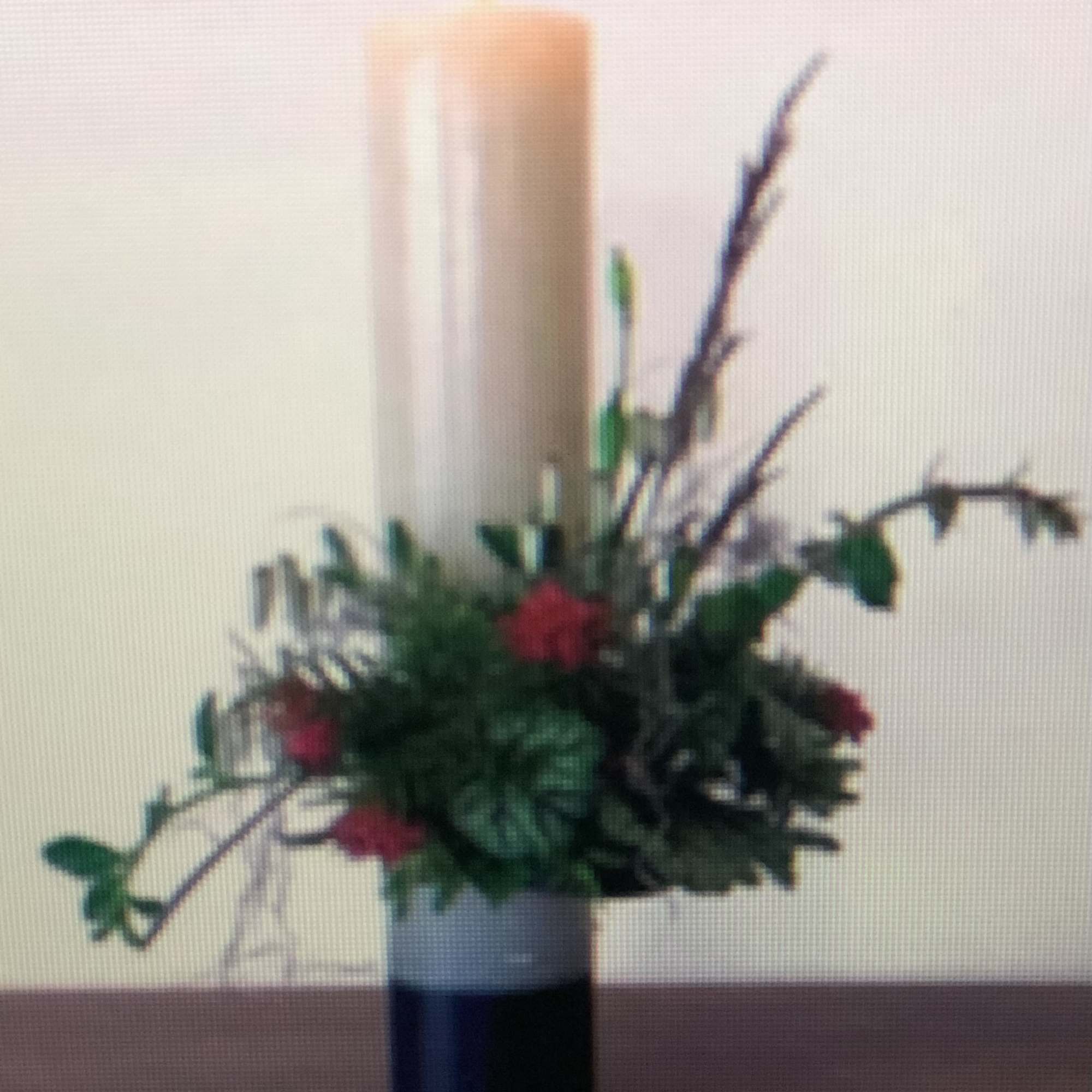 Tall candle arrangement with red flowers in a dark vase