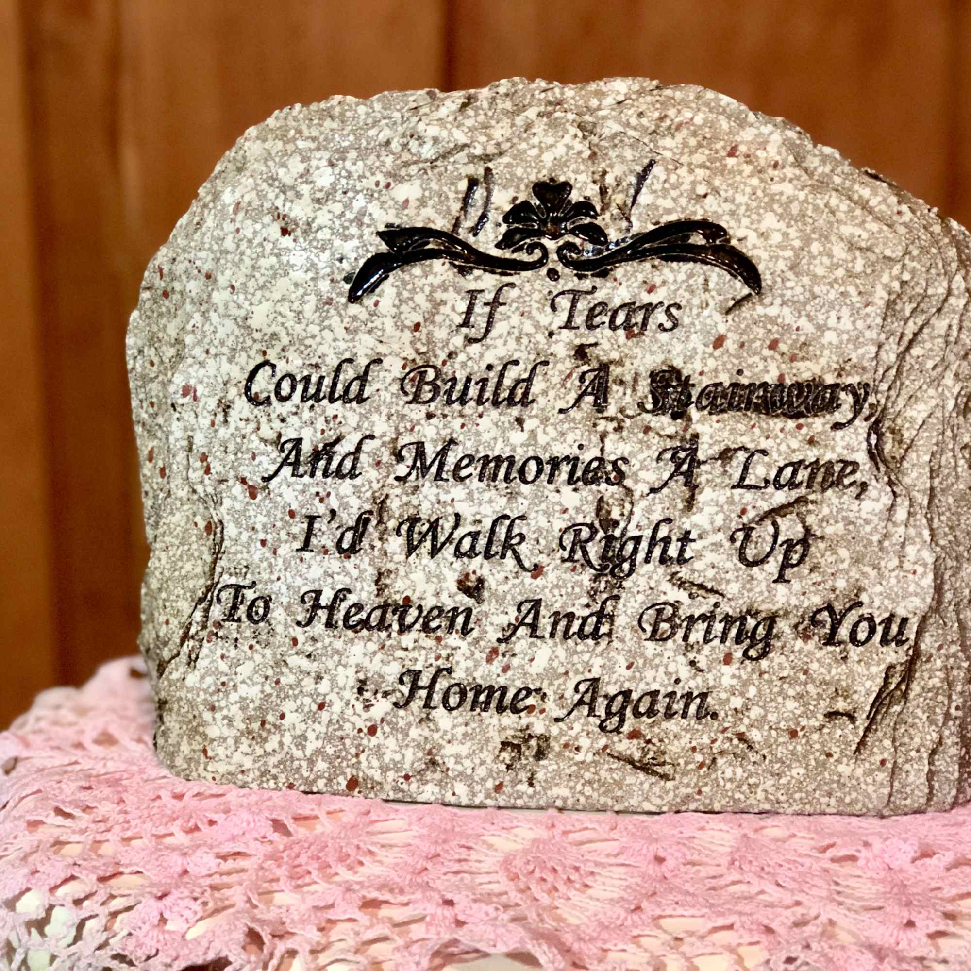 Memorial stone with an engraved sympathy poem on a pink crocheted cloth