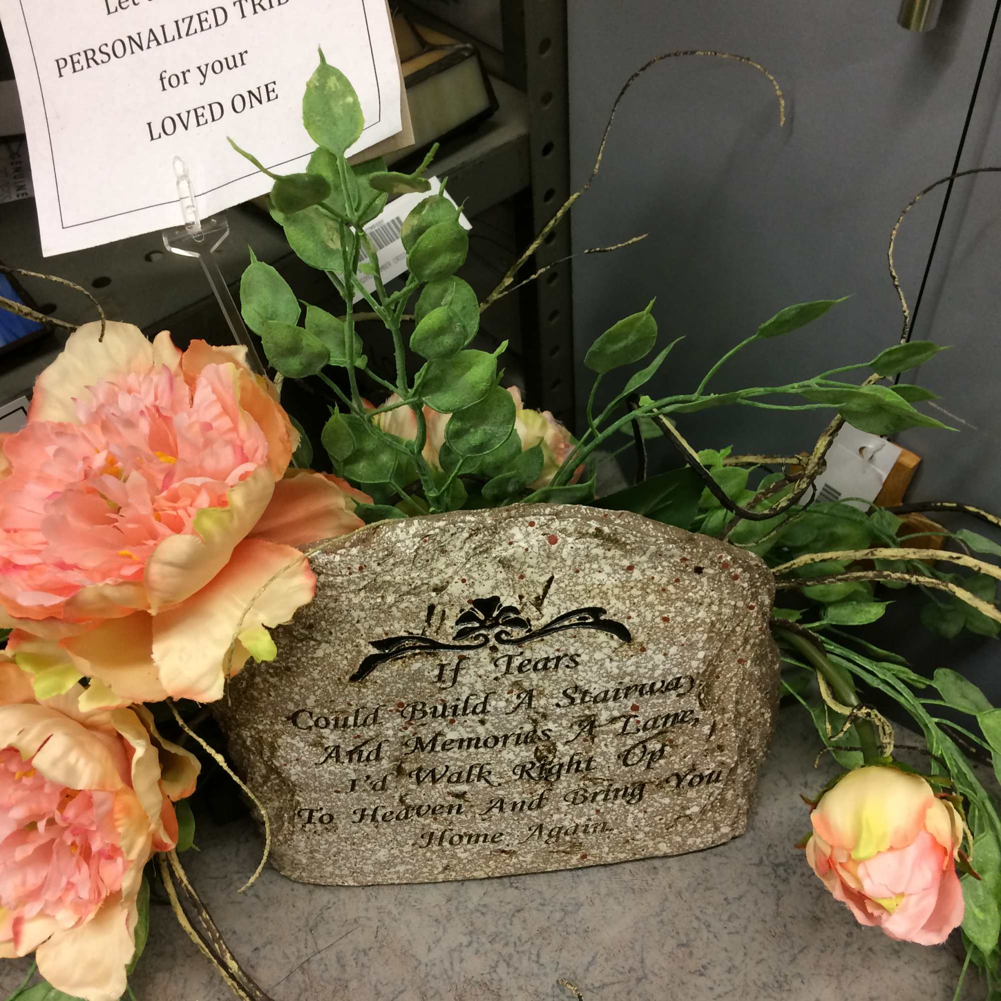Peach artificial flowers arranged around a memorial stone