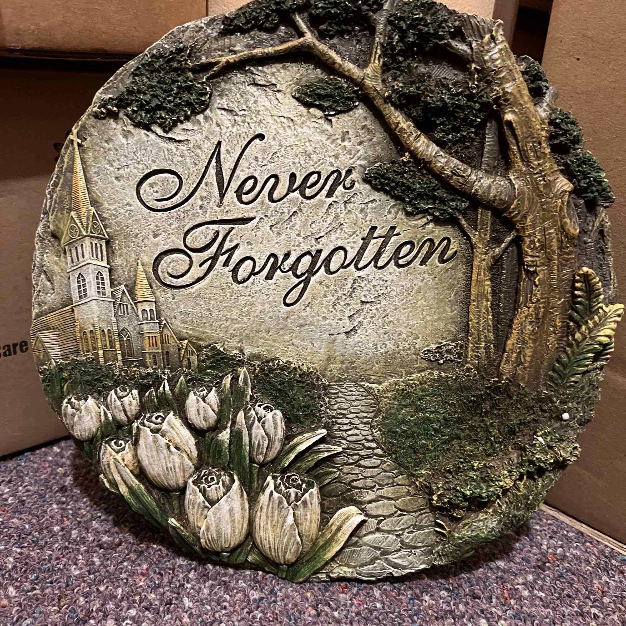 Decorative stone plaque with tulips and the words "Never Forgotten"