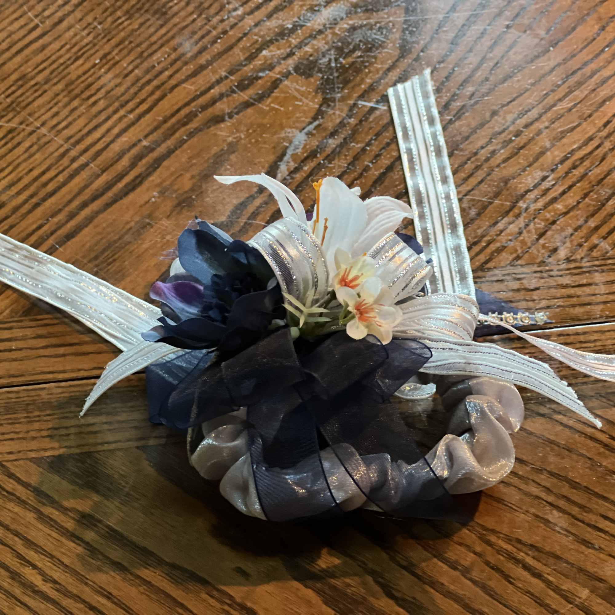 Small floral corsage with white and dark blue flowers and silver ribbons