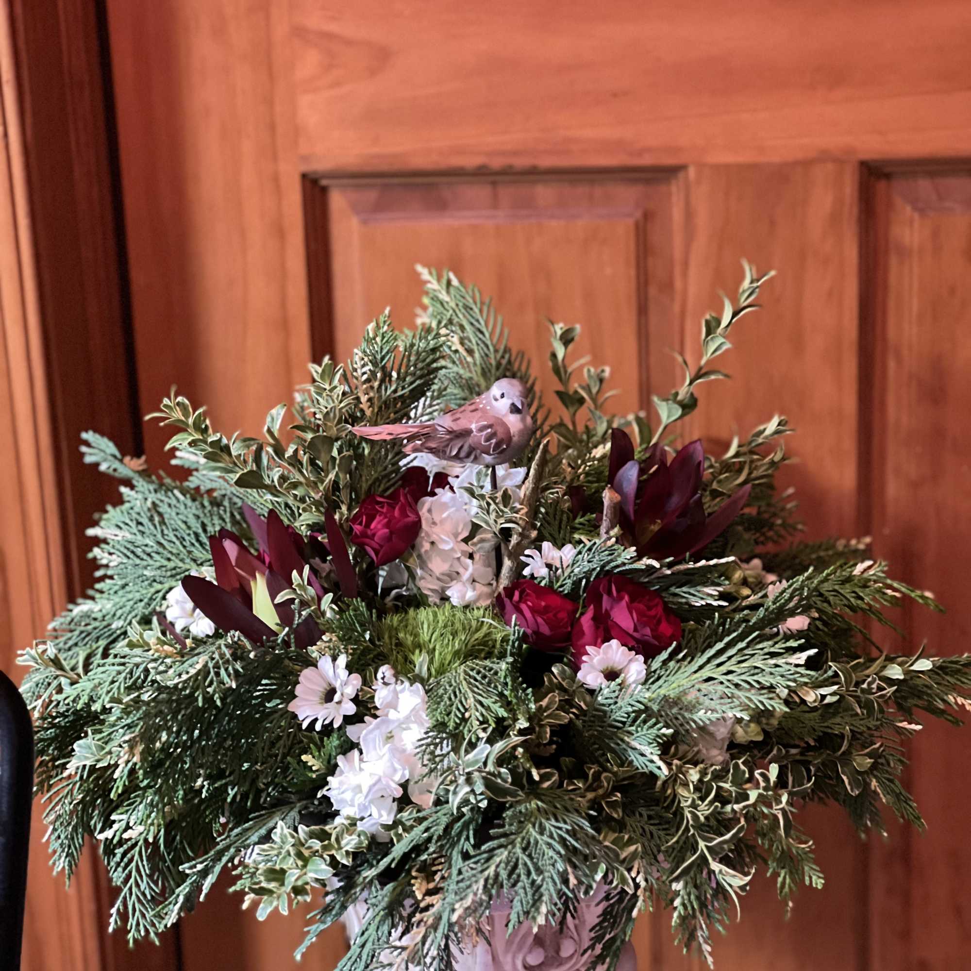 Mixed floral arrangement with red blooms and white flowers in a pedestal vase