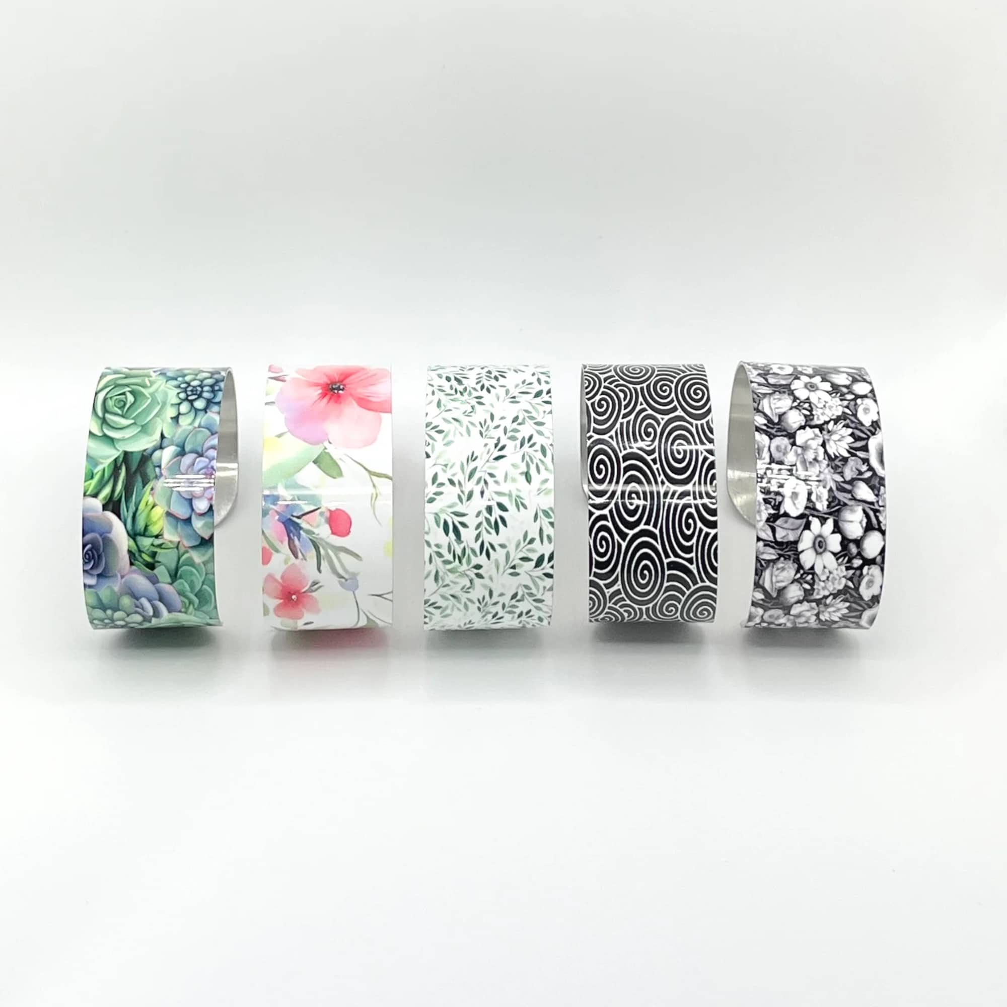 Five patterned floral tape rolls on a white background
