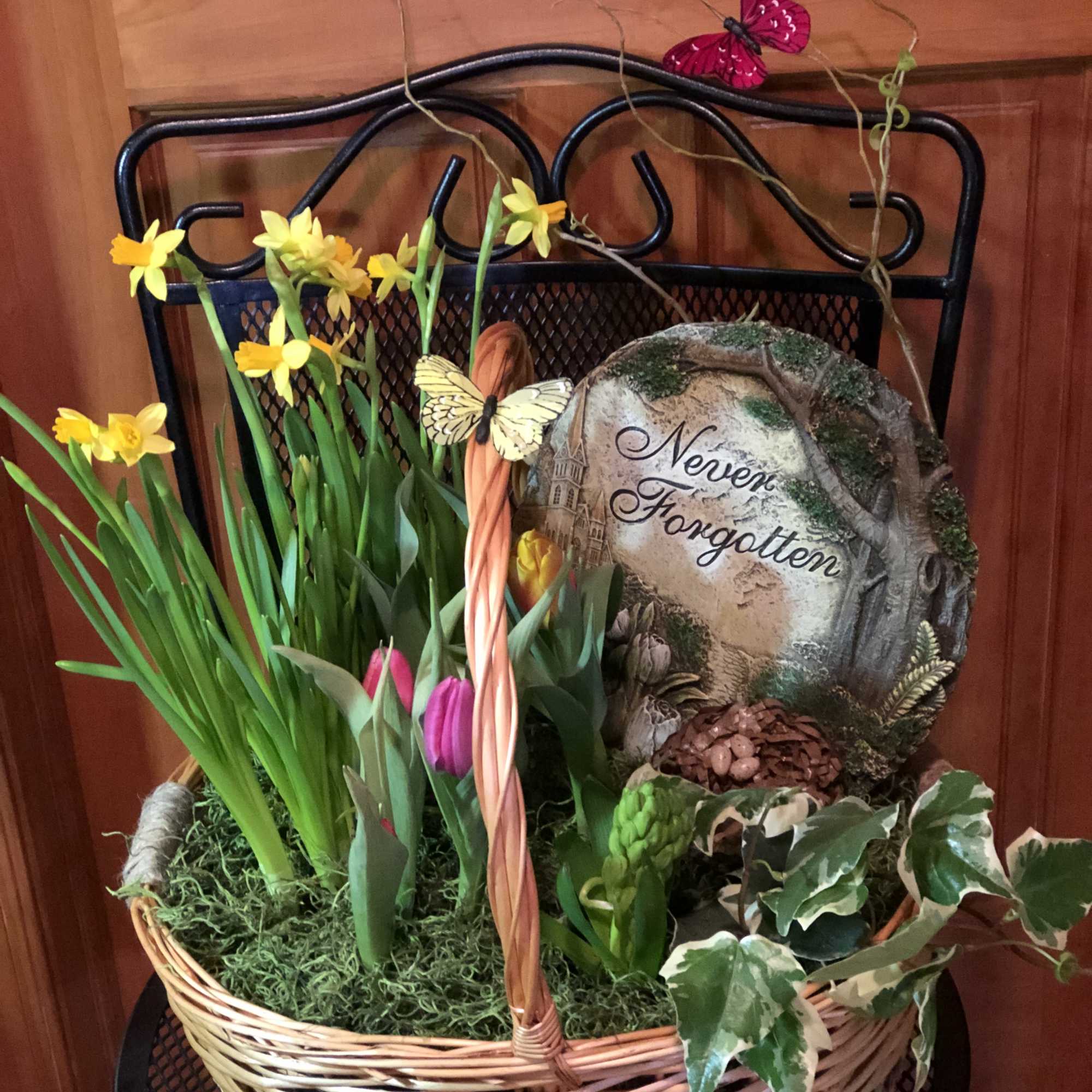 Basket of daffodils and tulips with a memorial stone reading Never Forgotten