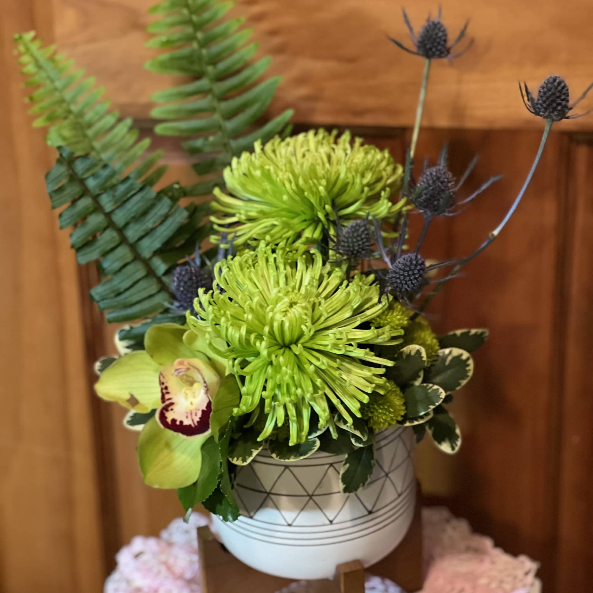 Green chrysanthemum arrangement in a patterned white vase