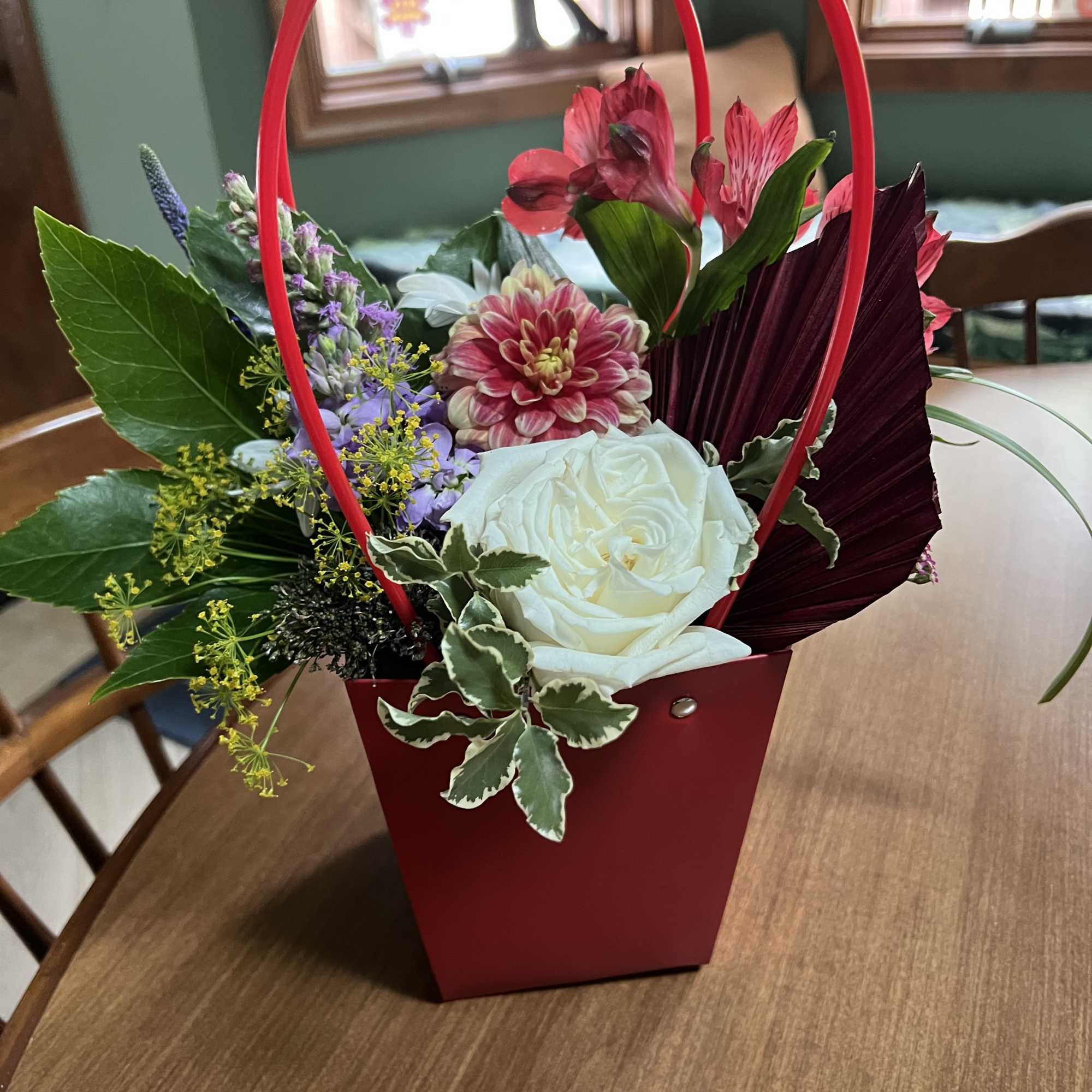 Mixed flower arrangement in a red handled container with white and pink blooms